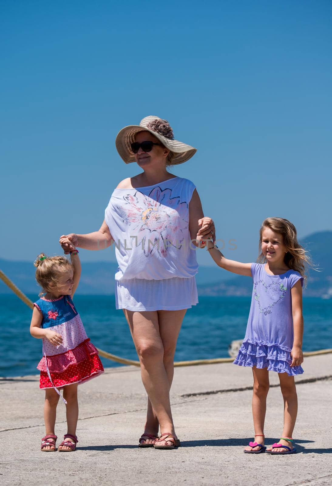Portrait of a grandmother with her cute little granddaughters by the sea by dotshock