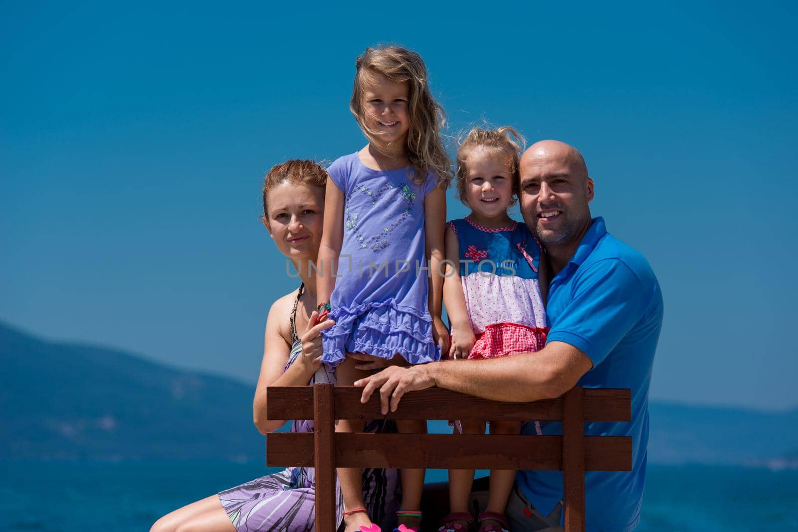 portrait of young happy family with daughters by the sea by dotshock