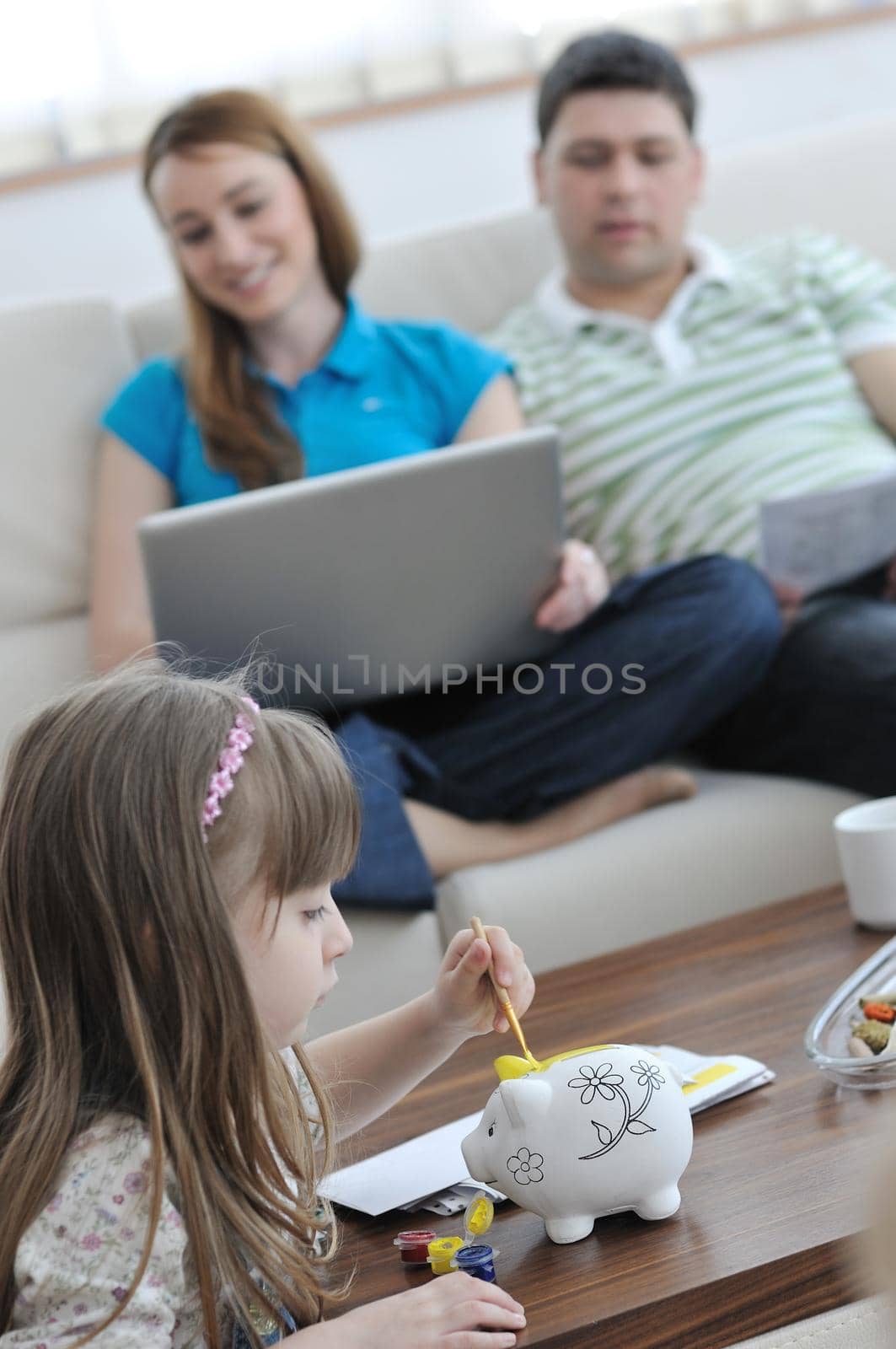 young parrent at home with beautiful child make savings and put coins money in piggy bank