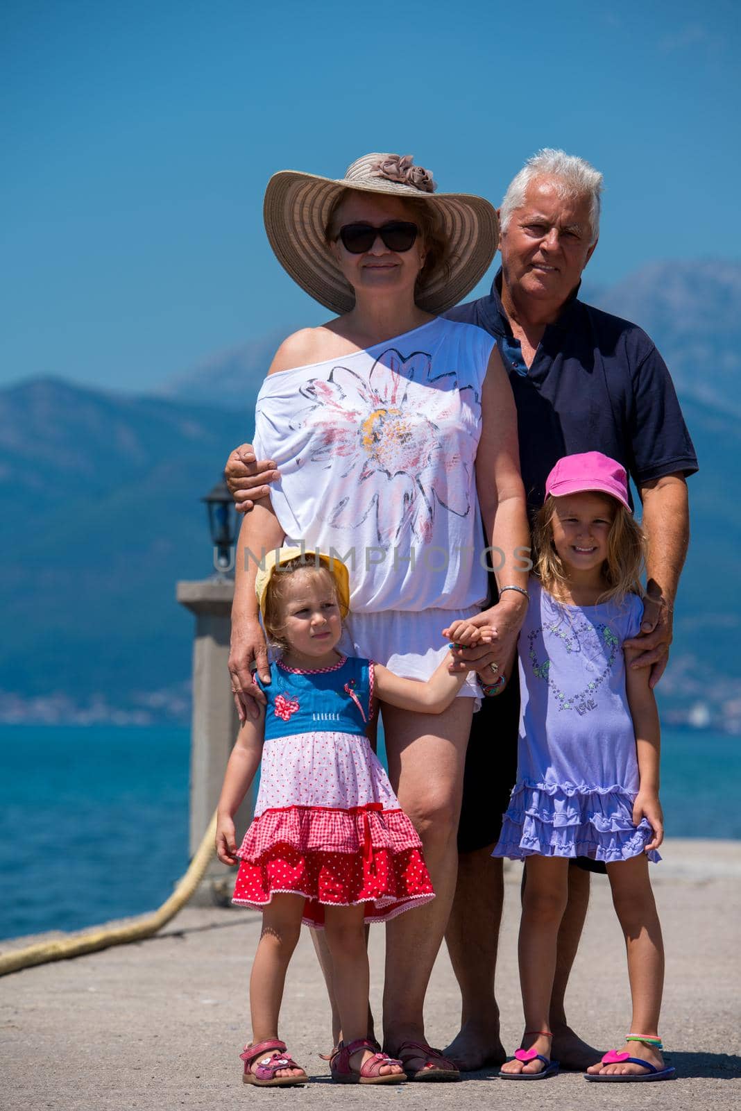 portrait of grandparents and granddaughters standing by the sea by dotshock