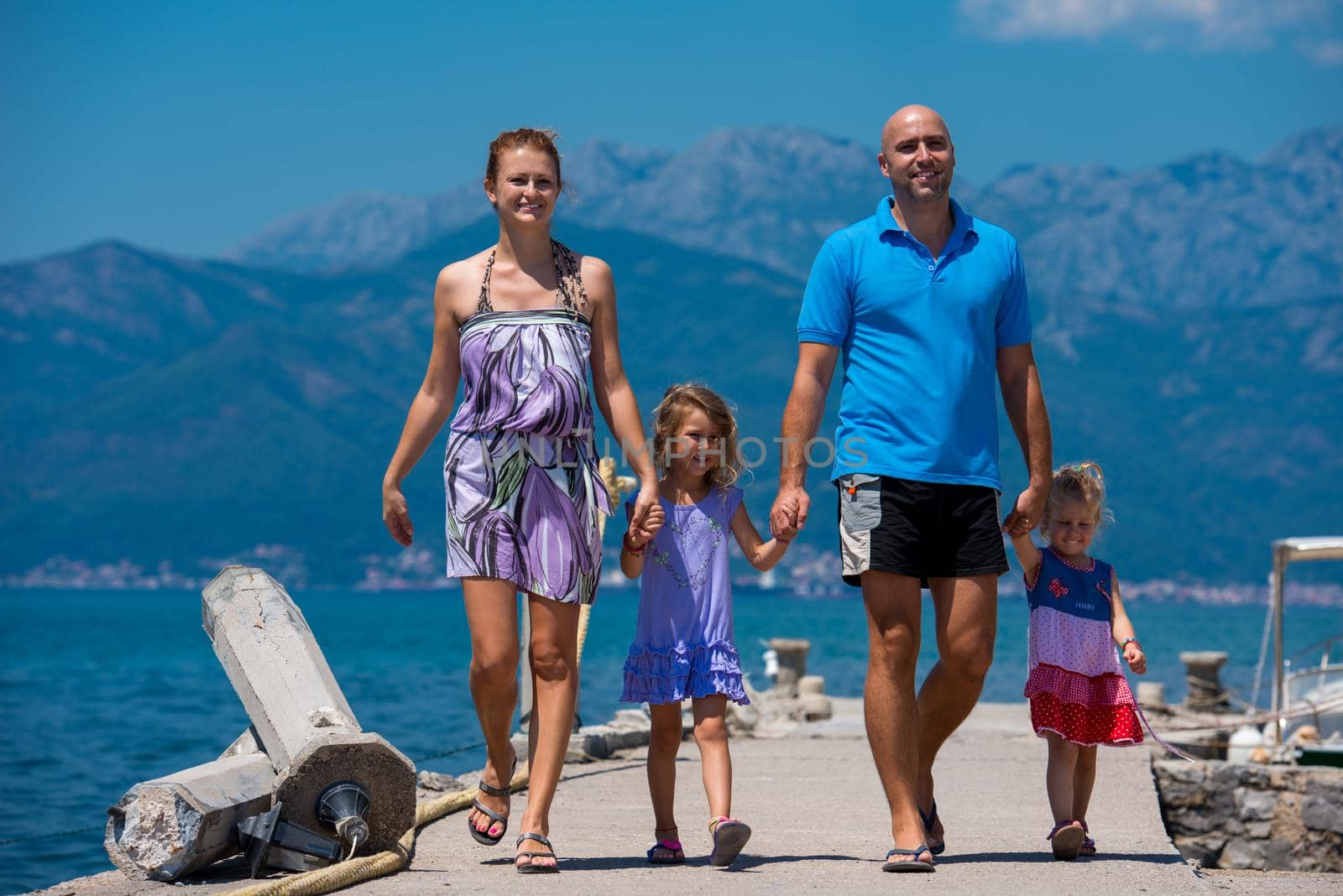 young happy family with cute little daughters holding their hands while walking by the sea during Summer vacation  Healthy family holiday concept