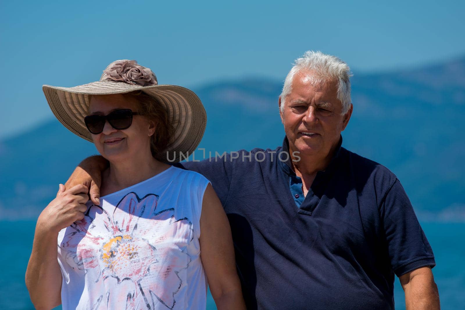 happy romantic senior couple hugging while walking  by the sea during Summer vacation