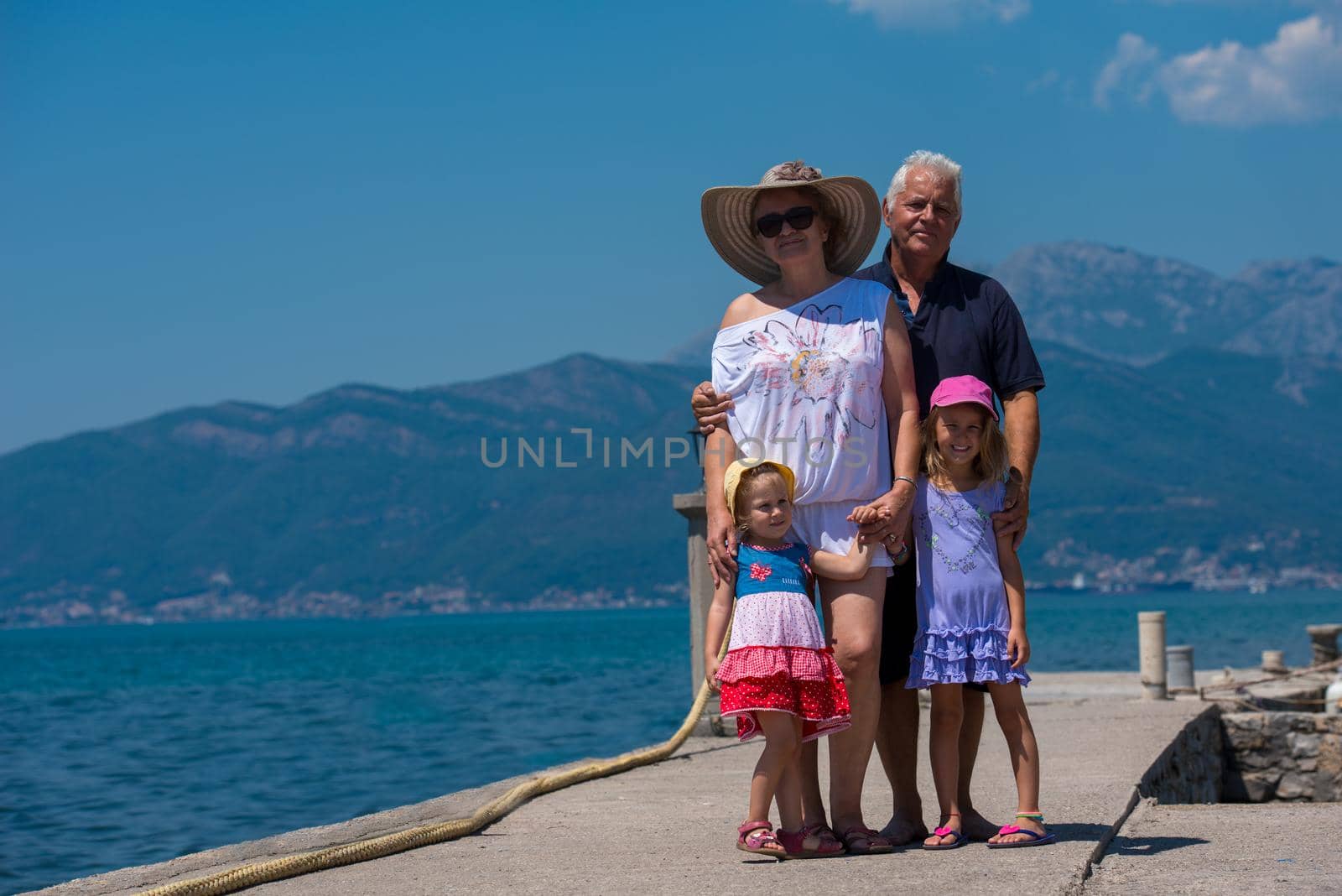 portrait of  happy grandparents with cute little granddaughters standing by the sea during Summer vacation  Healthy family holiday concept