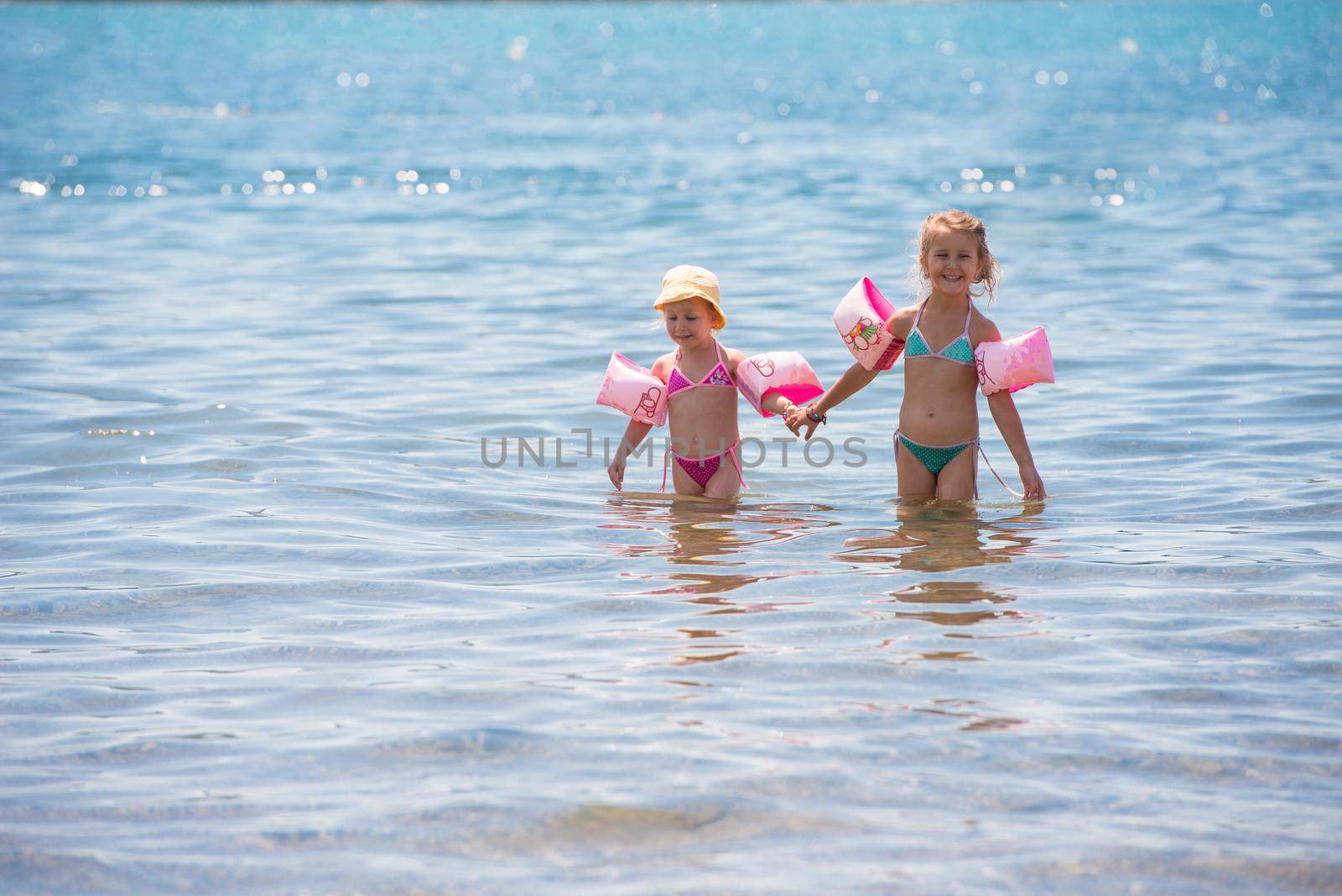 little girls with swimming armbands playing in shallow water by dotshock