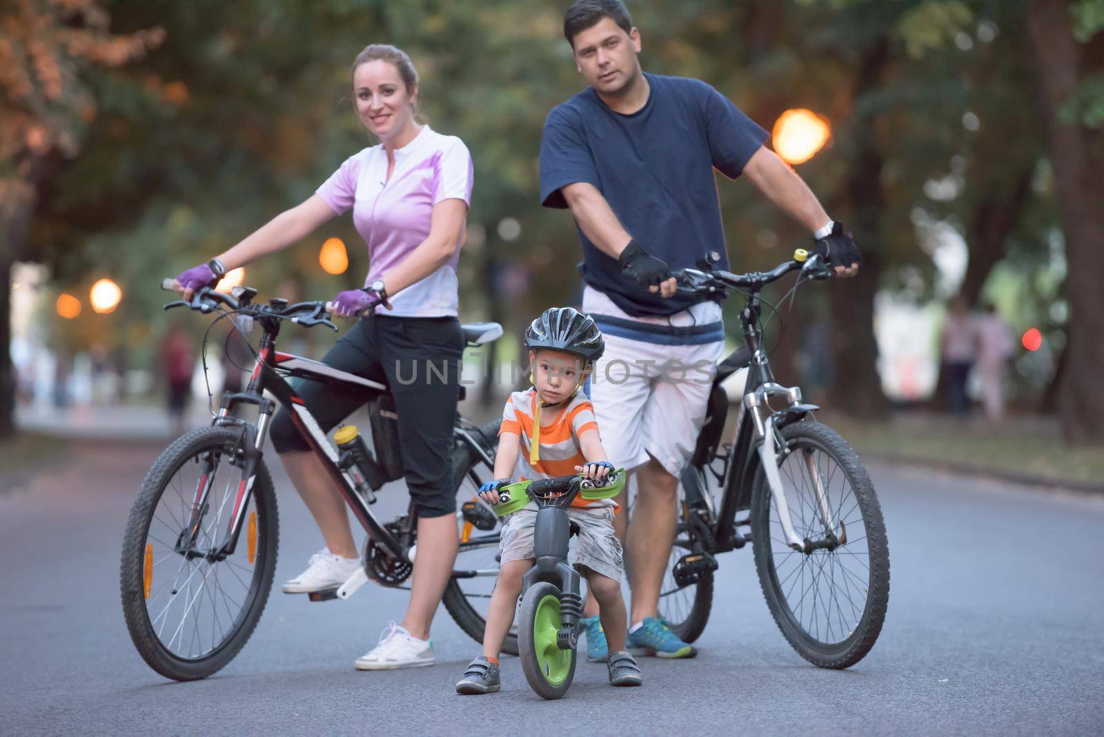 portrait of happy young family with bicycles in park at night