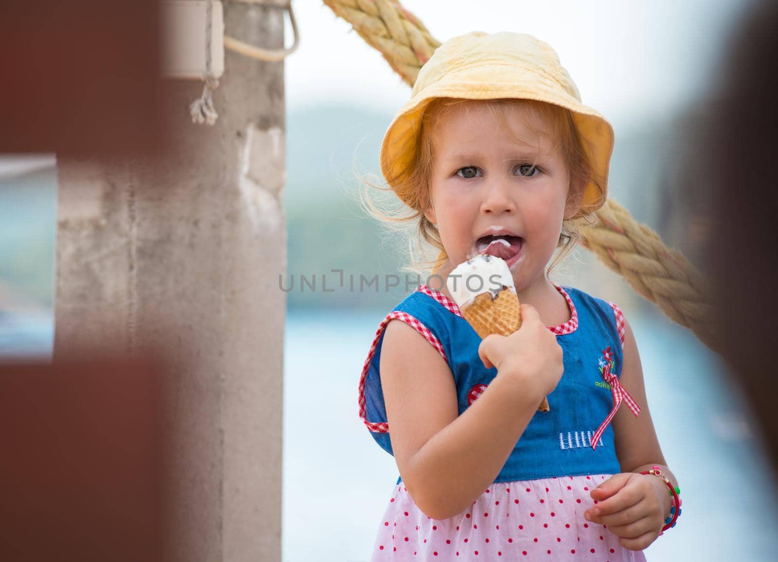adorable little girl eating ice cream on beach by the sea during Summer vacation