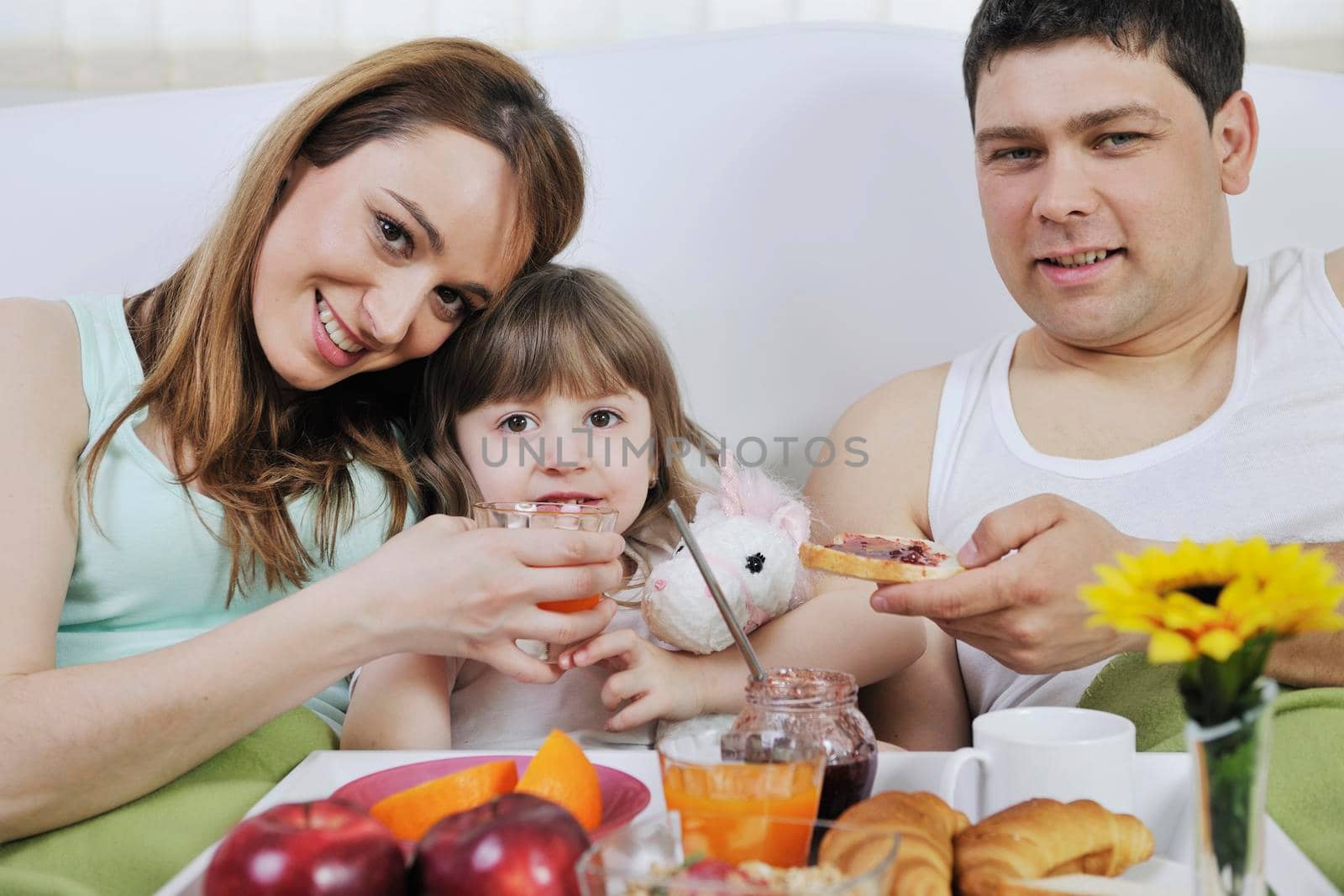 happy young family eat breakfast in bed at morning 