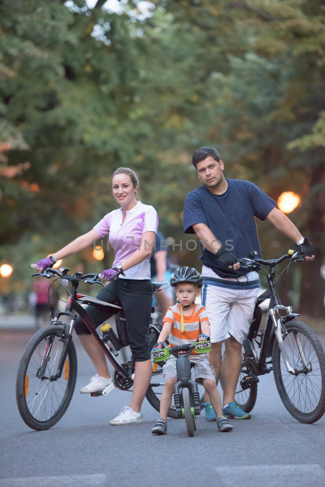 portrait of happy young family with bicycles in park at night