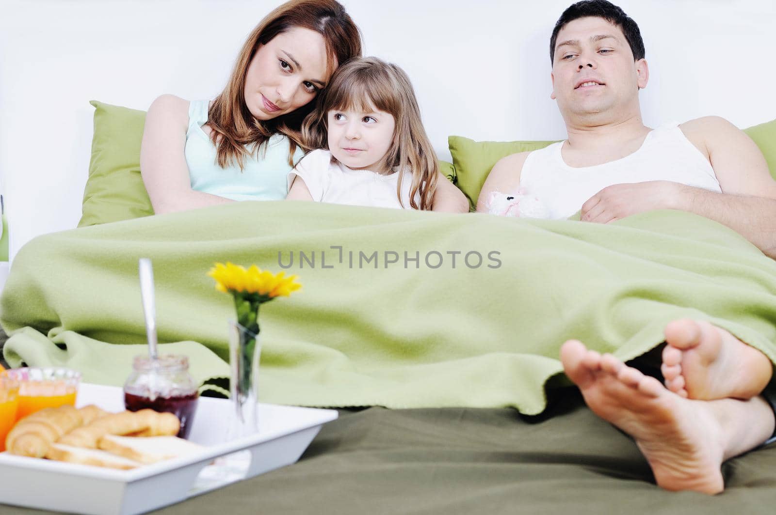 happy young family eat breakfast in bed by dotshock