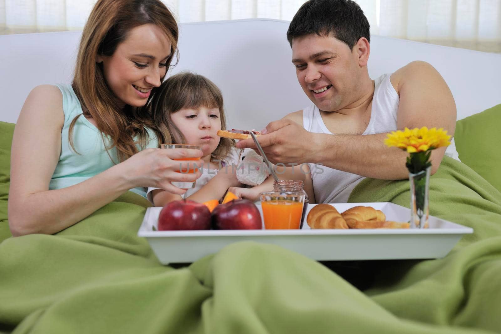 happy young family eat breakfast in bed at morning