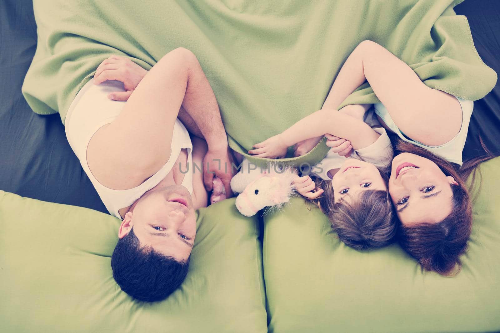 happy young family relaxing in bed 