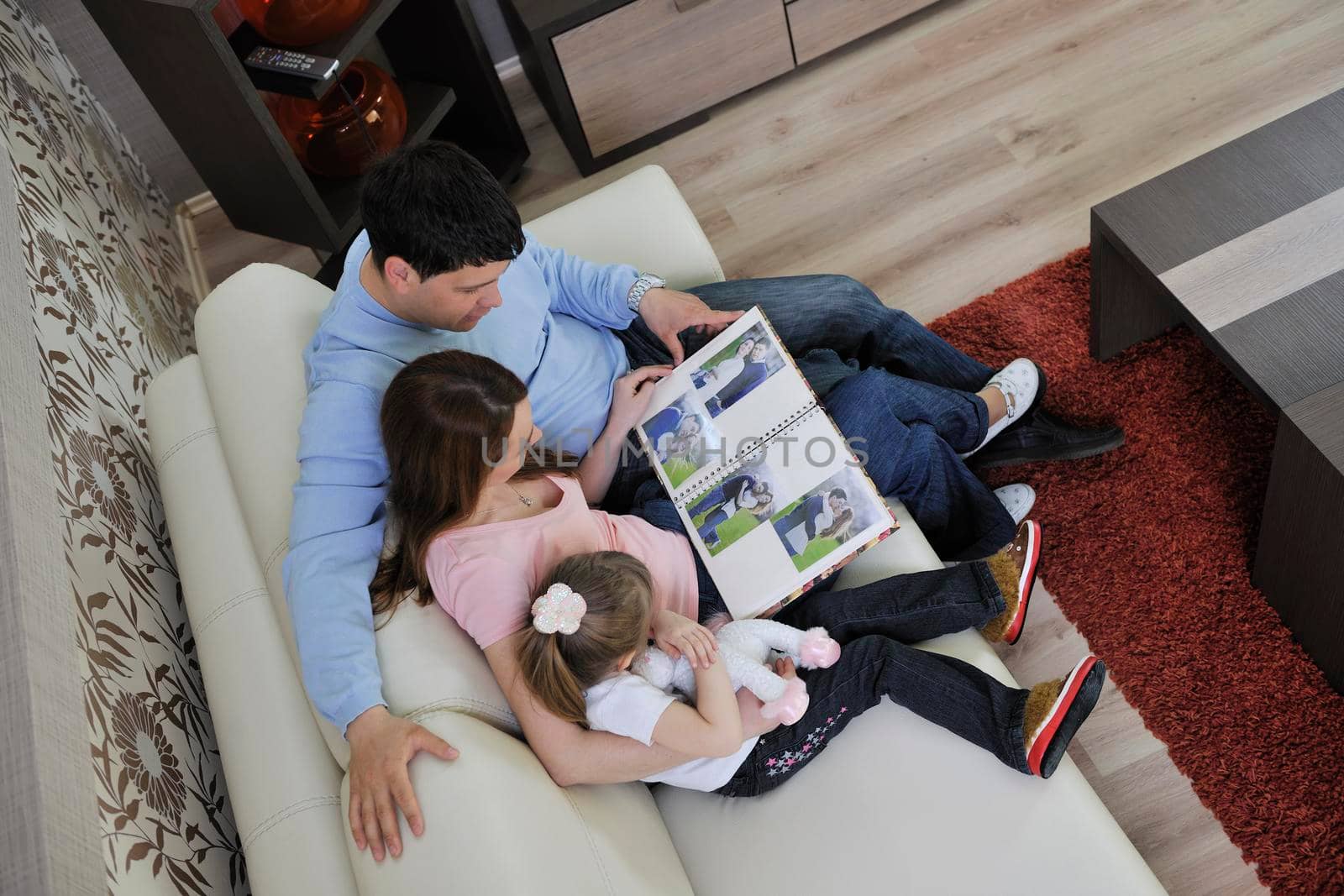 happy young family looking old pictures in photo album at home