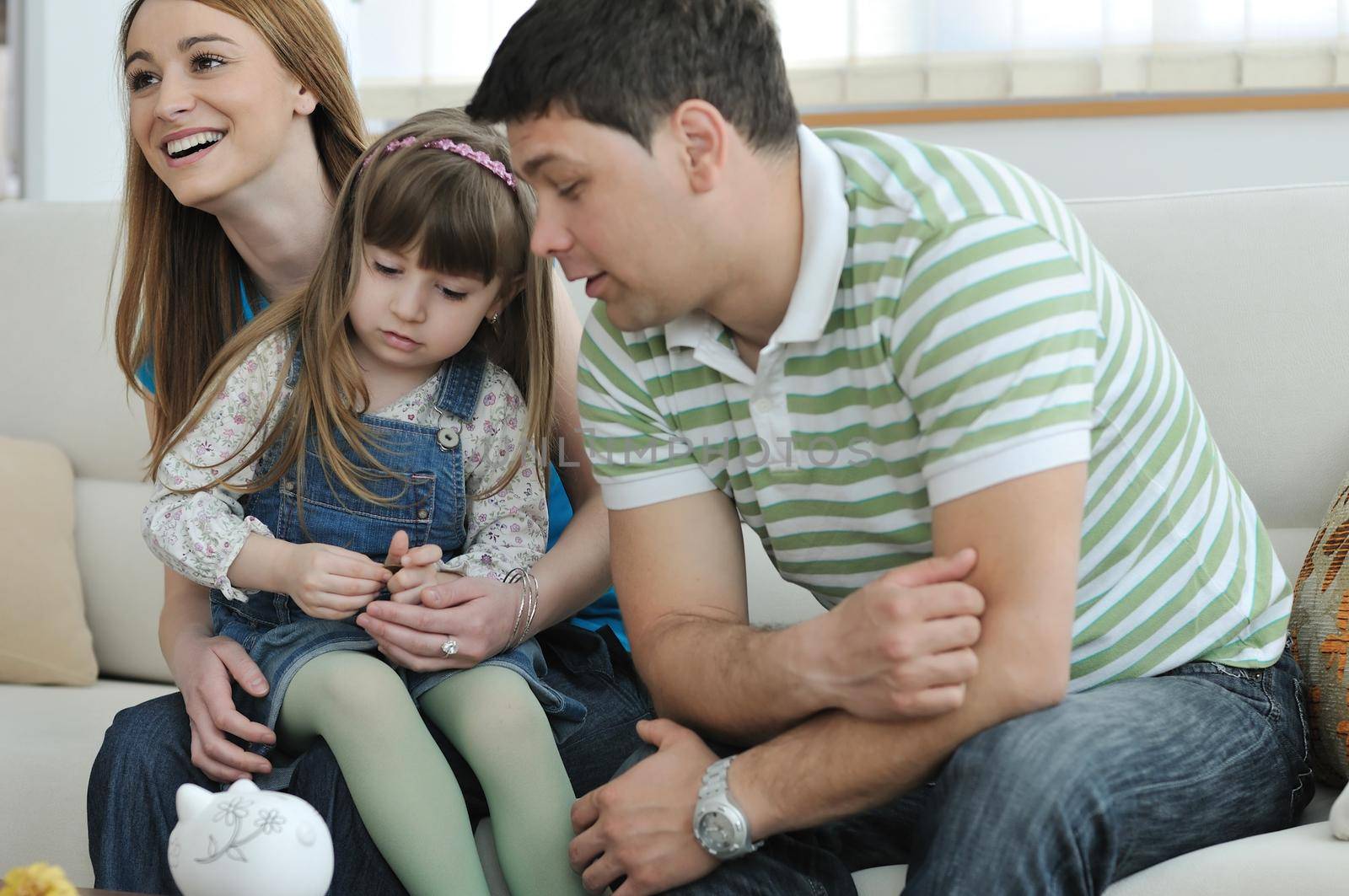 young parrent at home with beautiful child make savings and put coins money in piggy bank