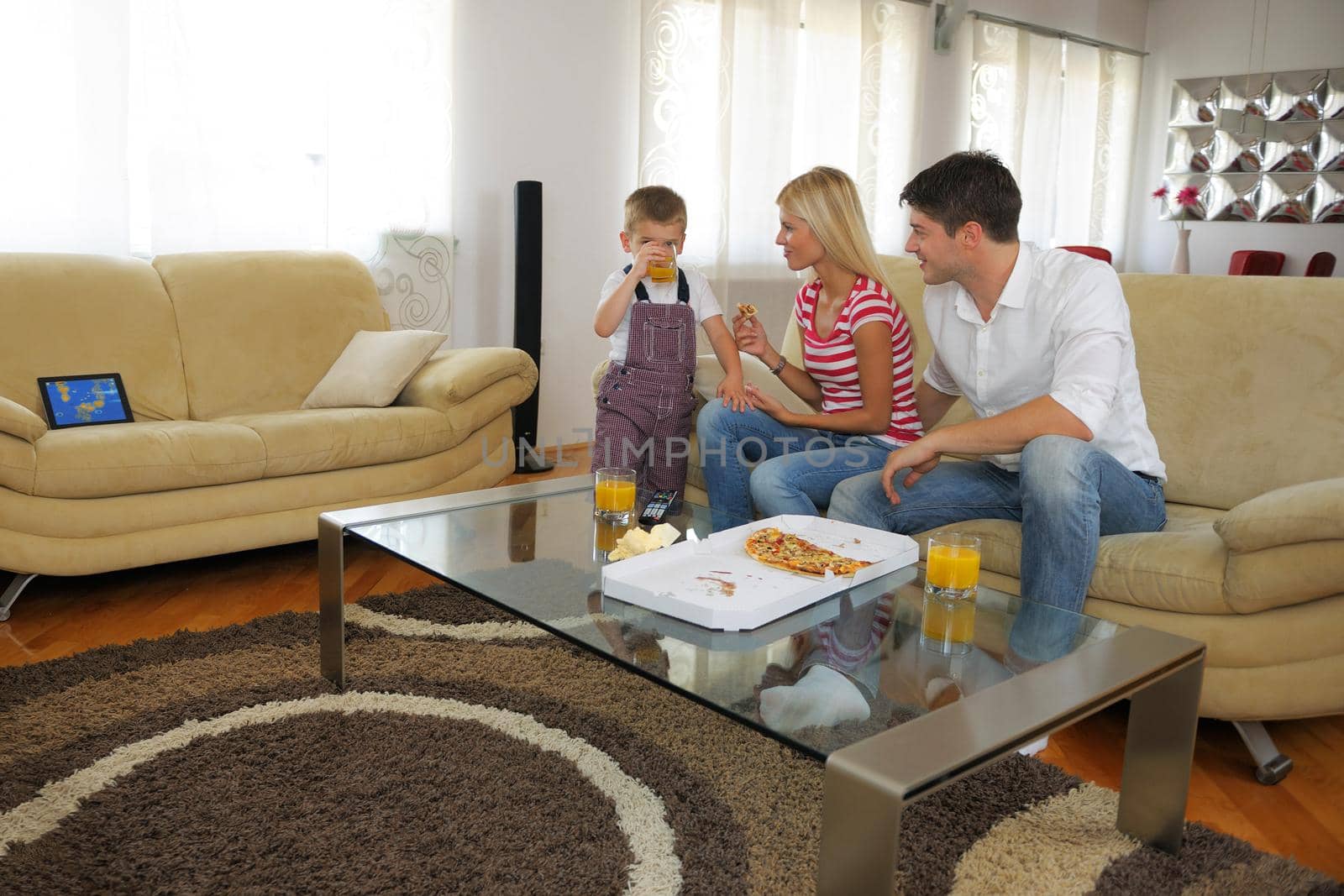 happy young family eating tasty pizza with cheesa and dring healthy and fresh orange juice