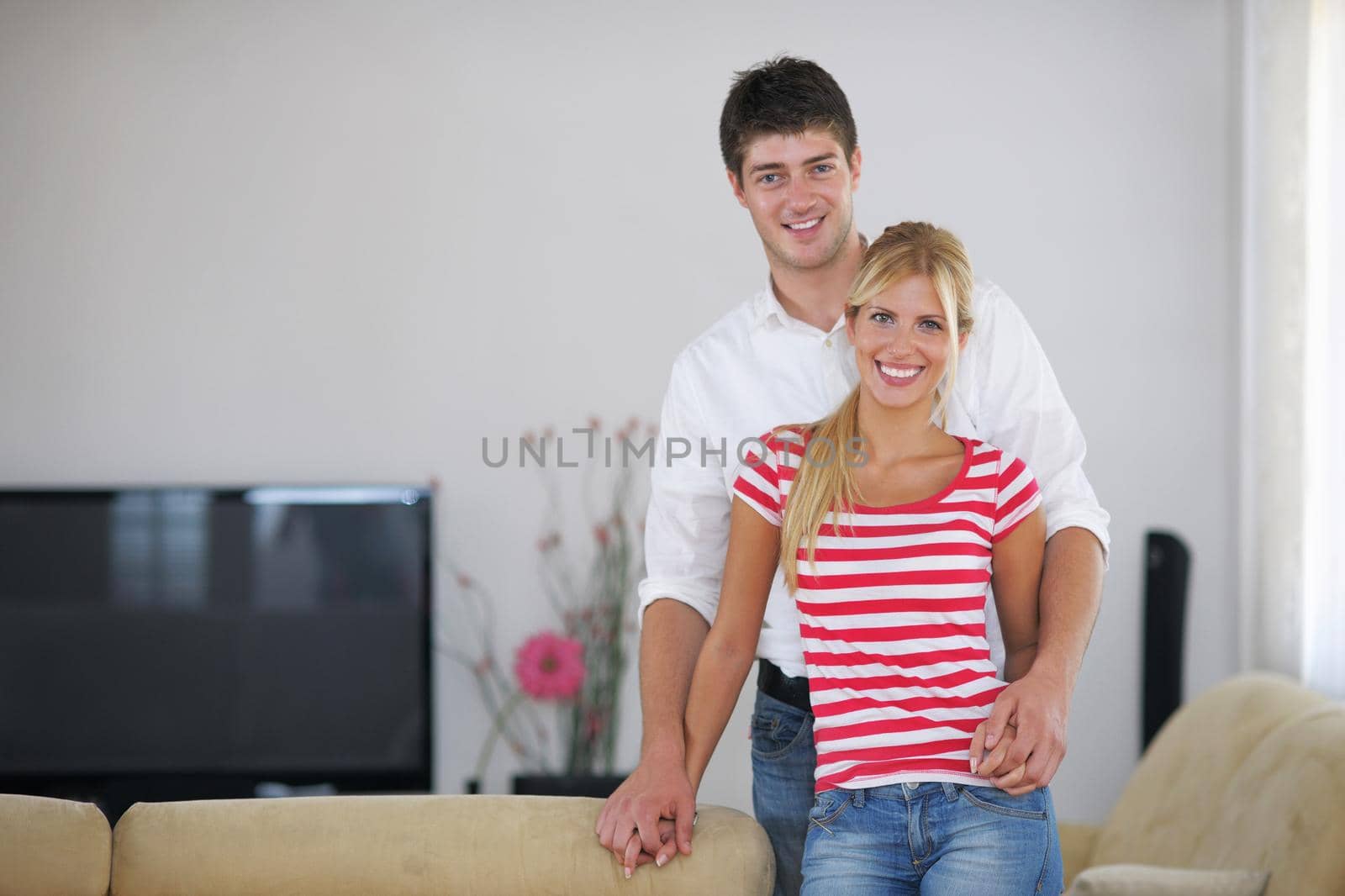 Relaxed young  couple watching tv at home in bright living room