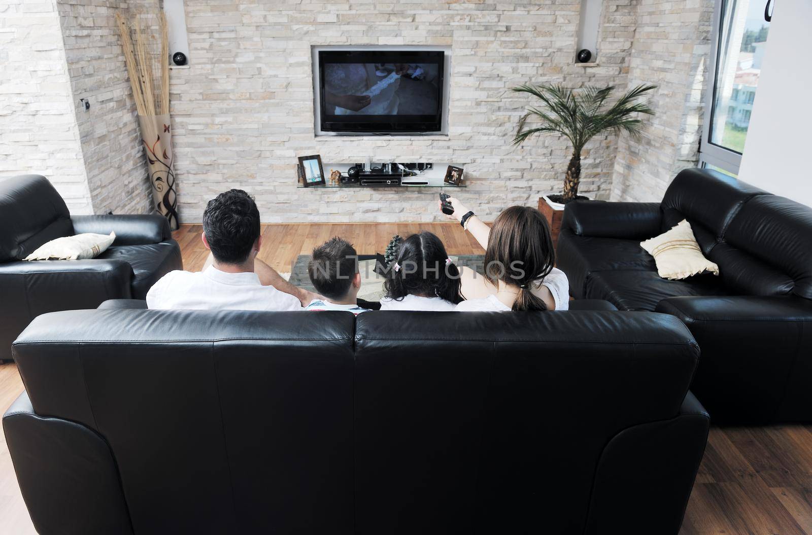 happy young family wathching flat tv at modern home indoor