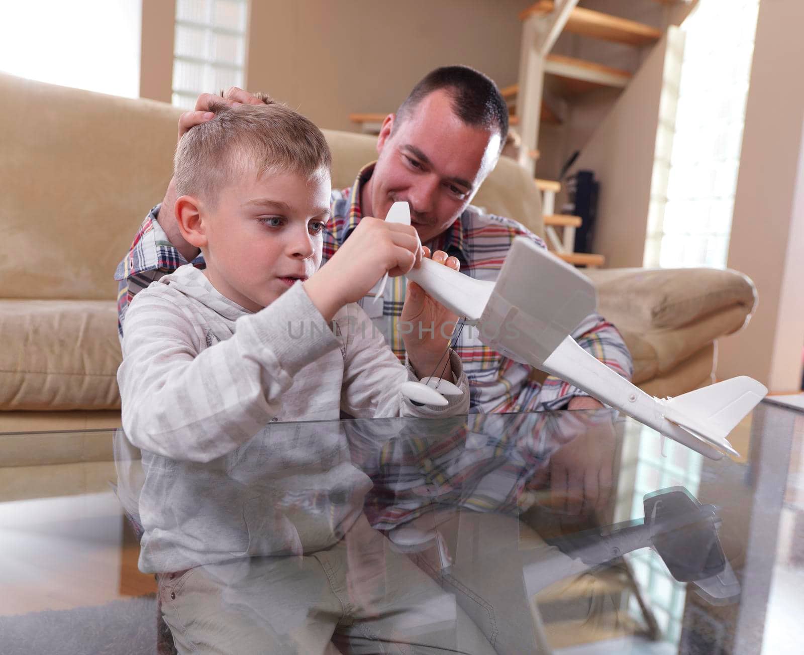 father and son assembling airplane toy at modern home living room indoor