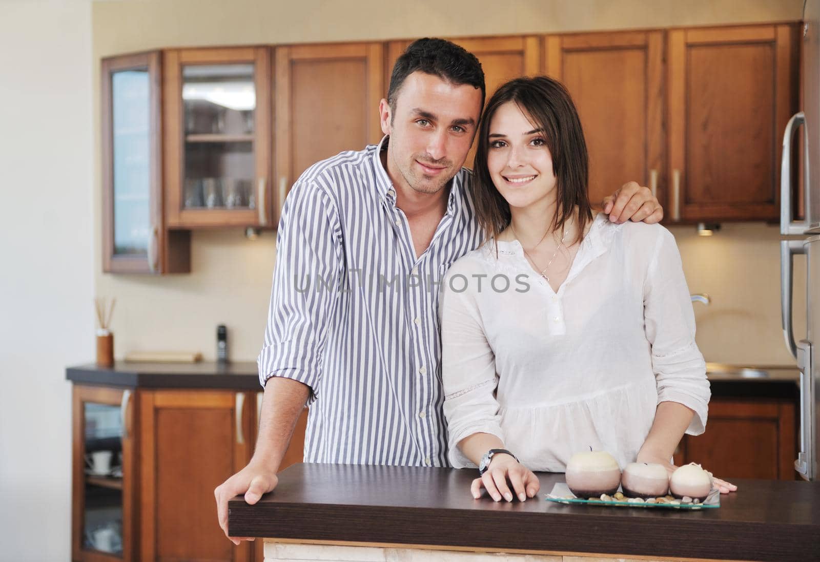 happy young couple have fun in modern wooden  kitchen indoor while preparing fresh food