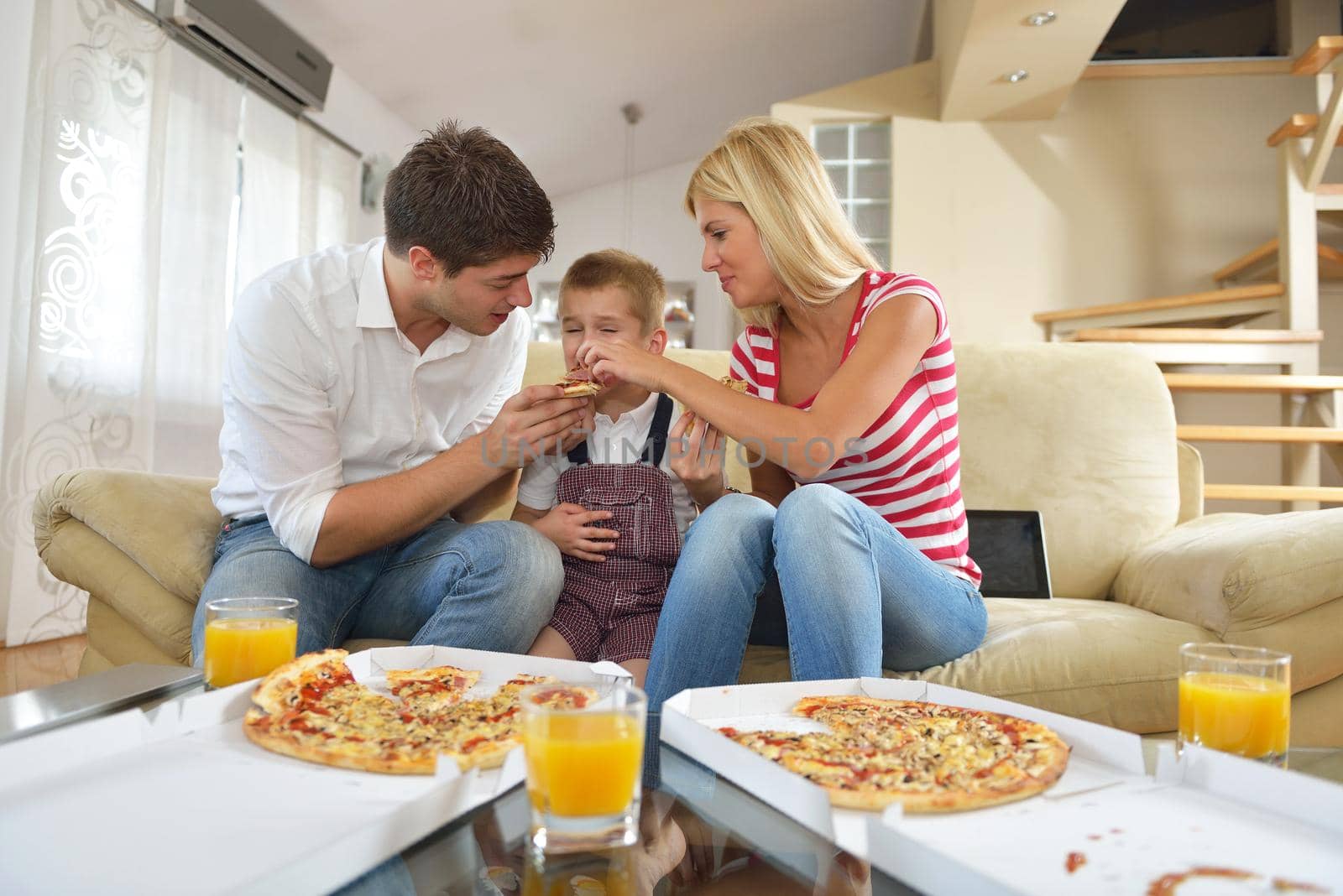 happy young family eating tasty pizza with cheesa and dring healthy and fresh orange juice