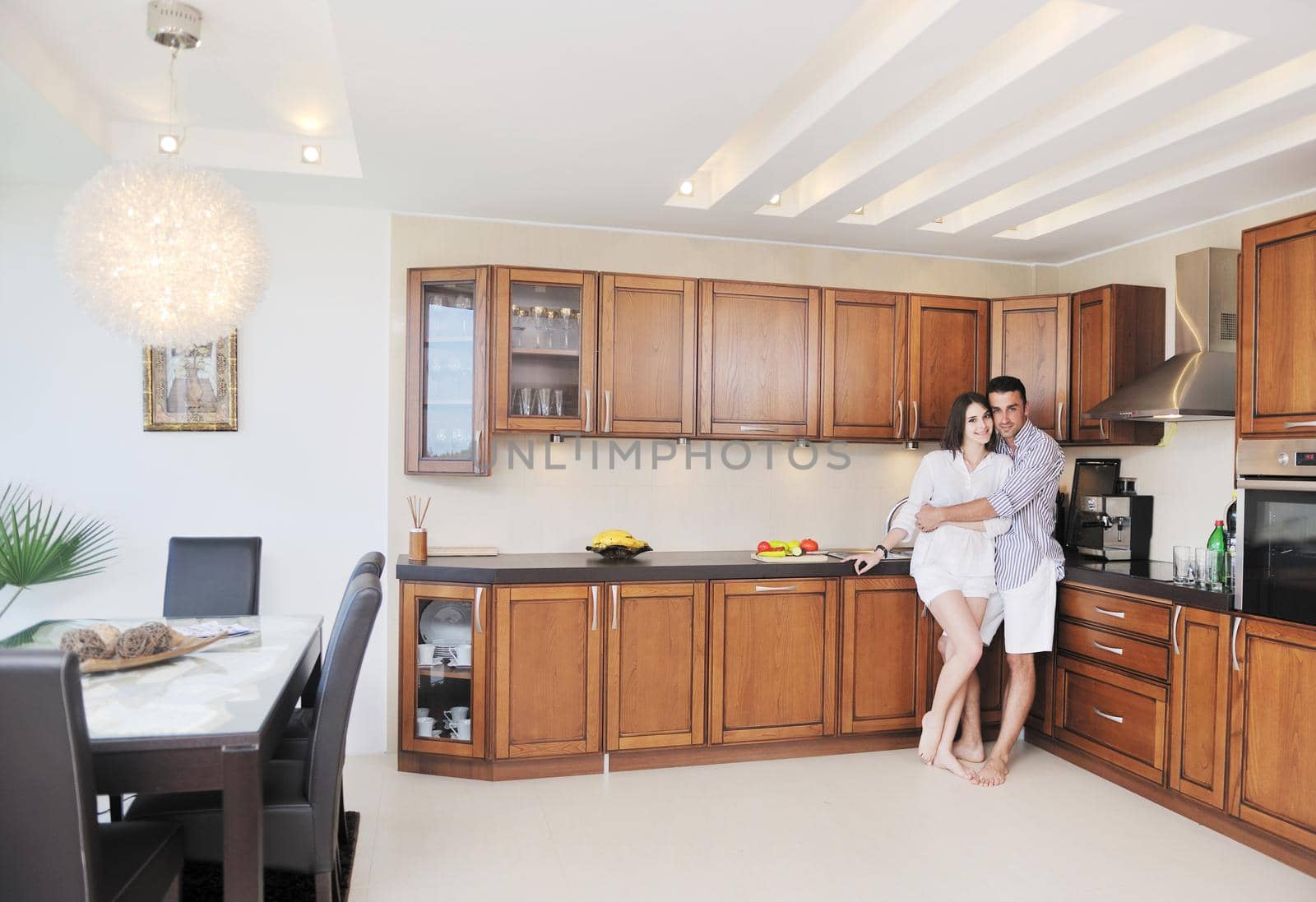 happy young couple have fun in modern wooden  kitchen indoor while preparing fresh food