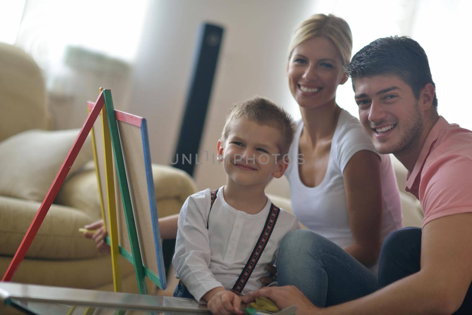 happy young family teach leassons and prepare their son for school while draw on board at home