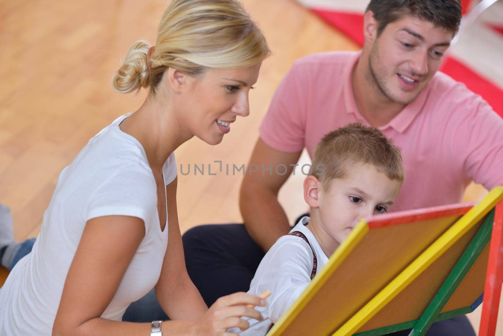 happy young family teach leassons and prepare their son for school while draw on board at home