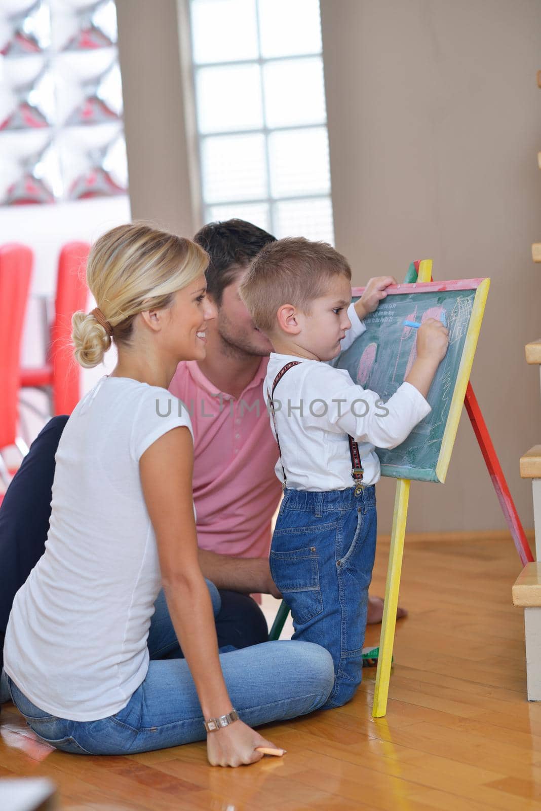 happy young family teach leassons and prepare their son for school while draw on board at home