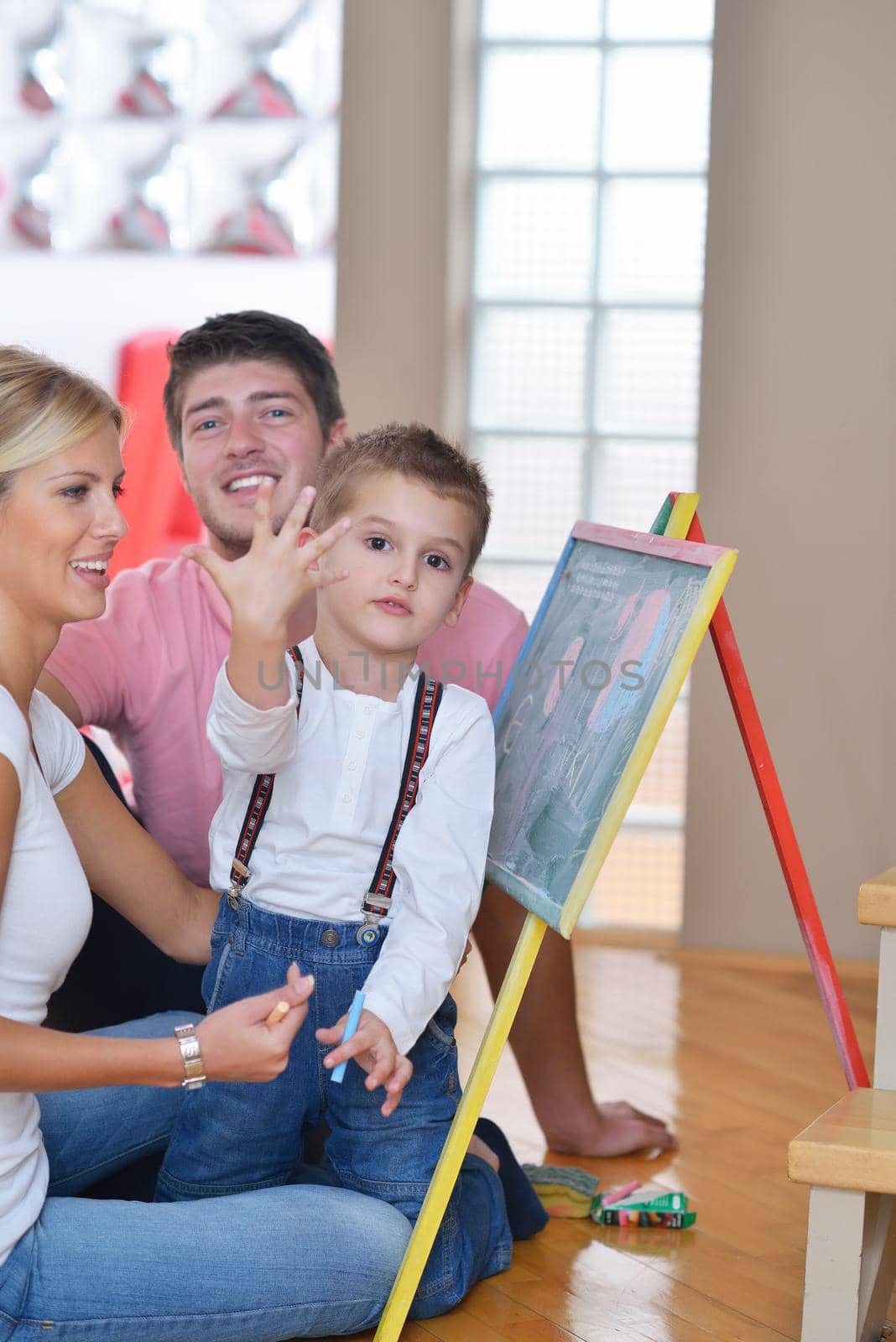 happy young family teach leassons and prepare their son for school while draw on board at home