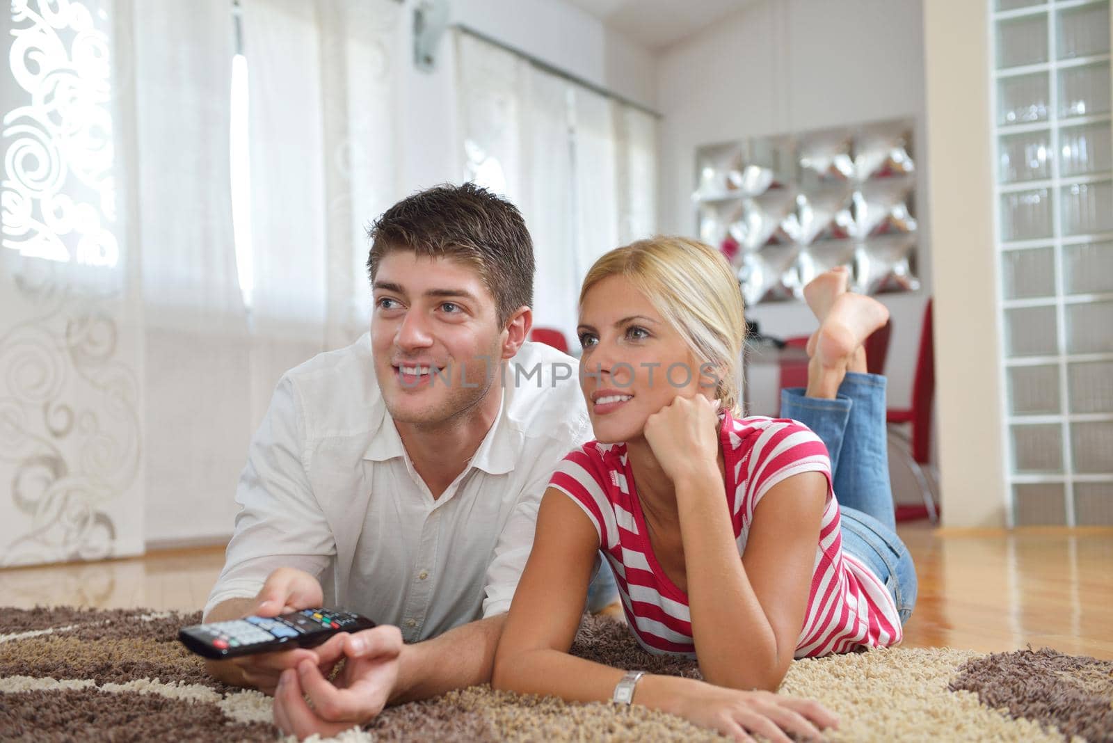 Relaxed young  couple watching tv at home in bright living room