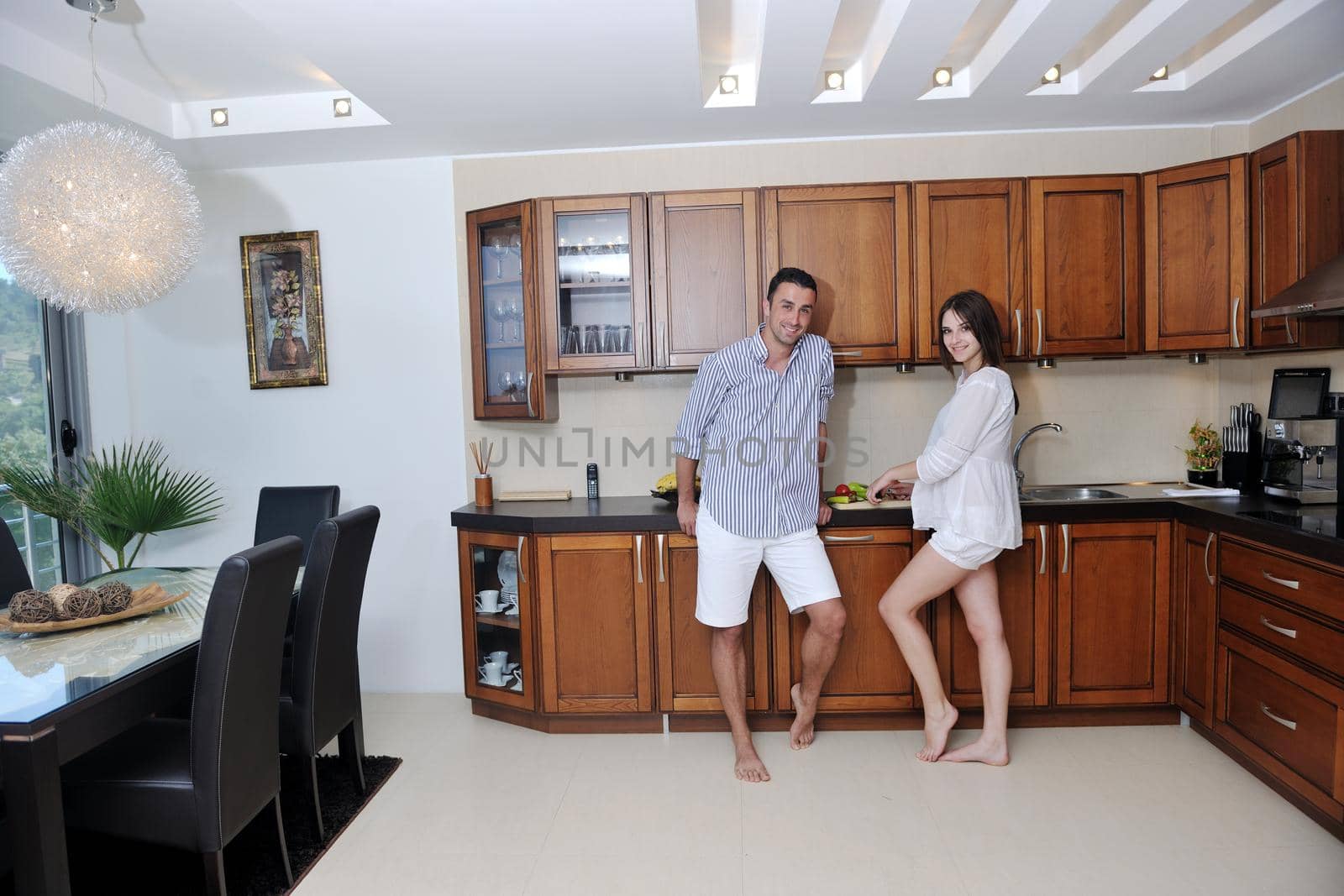 happy young couple have fun in modern wooden  kitchen indoor while preparing fresh food