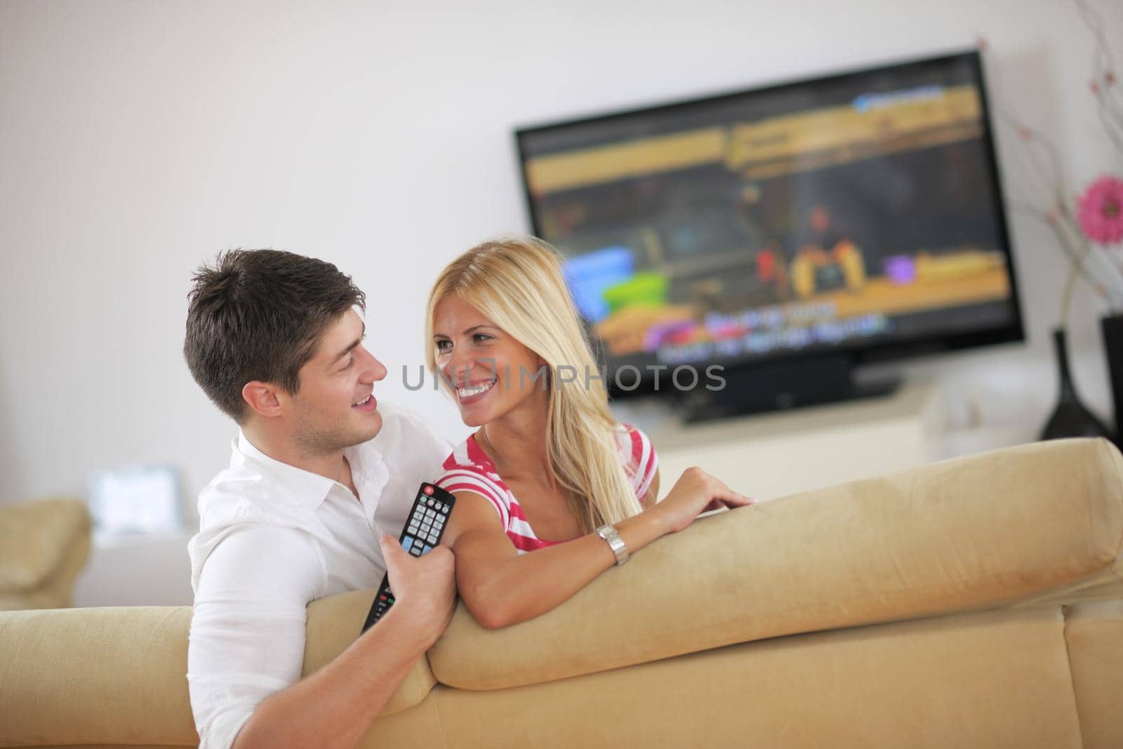 Relaxed young  couple watching tv at home in bright living room