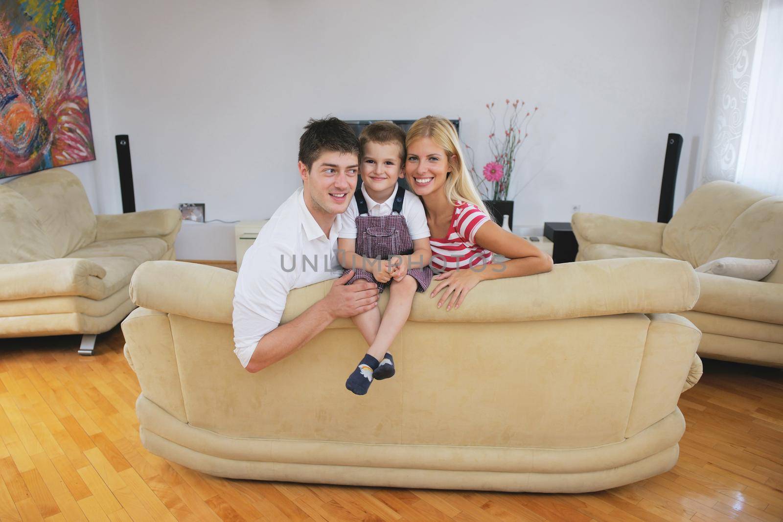 happy young family with kids in bright modern living room have fun and looking big flat lcd tv