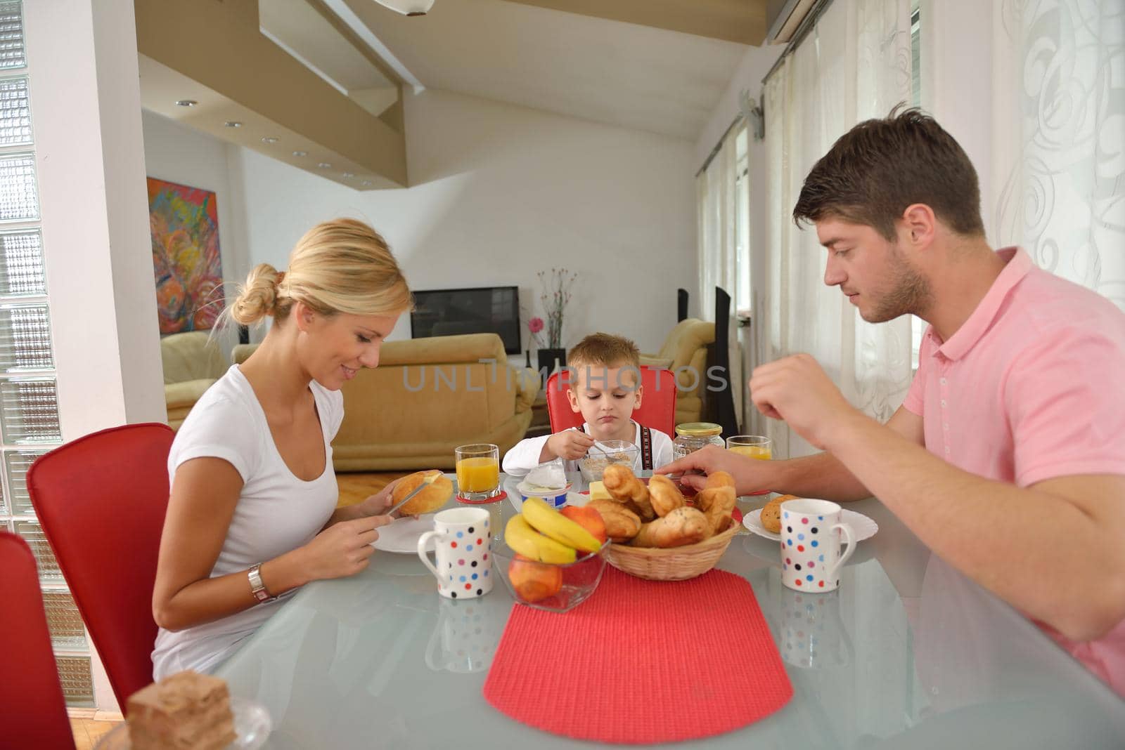 happy young family have healthy breakfast at kitchen with red details on bright morning light