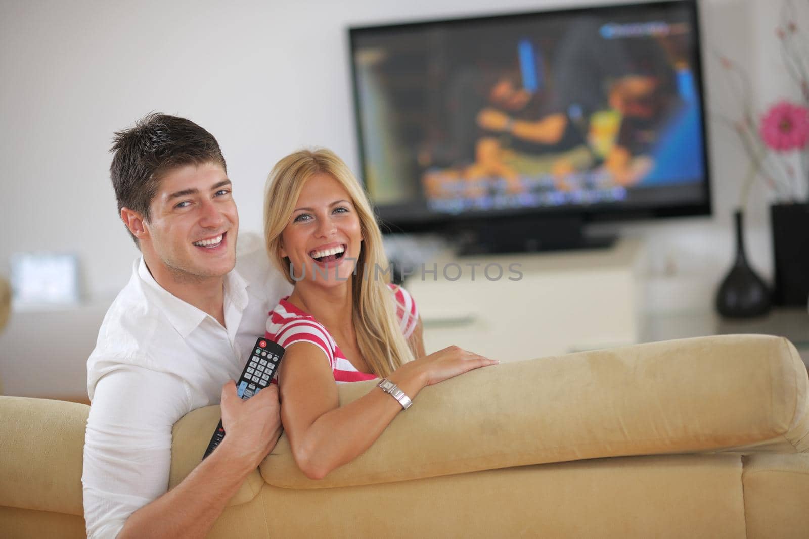 Relaxed young  couple watching tv at home in bright living room