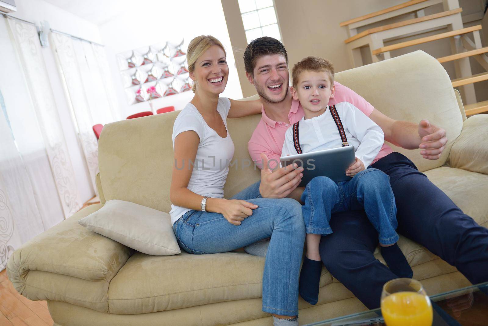 happy young family using tablet computer at modern  home for playing games and education