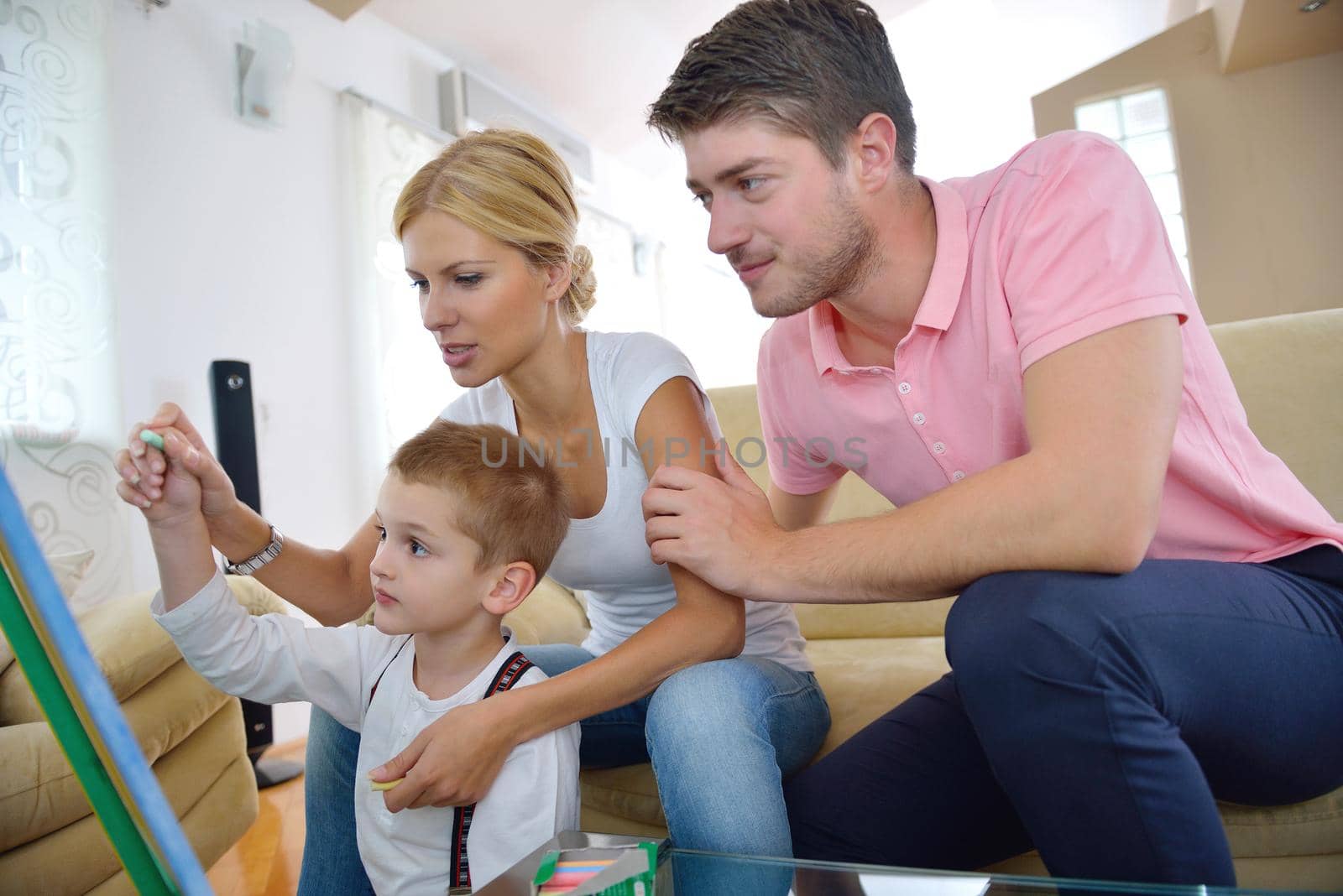 happy young family teach leassons and prepare their son for school while draw on board at home