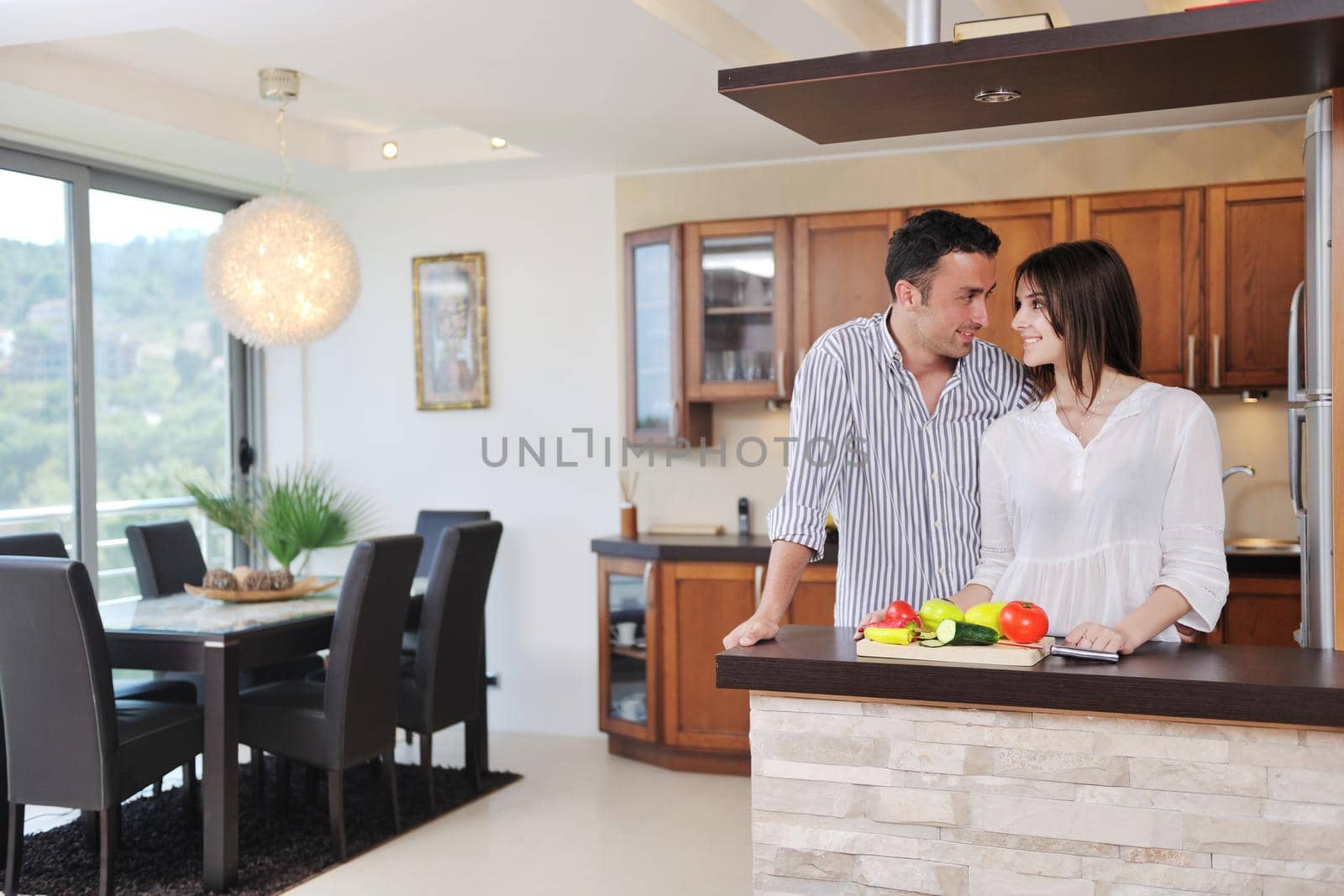 happy young couple have fun in modern wooden  kitchen indoor while preparing fresh food