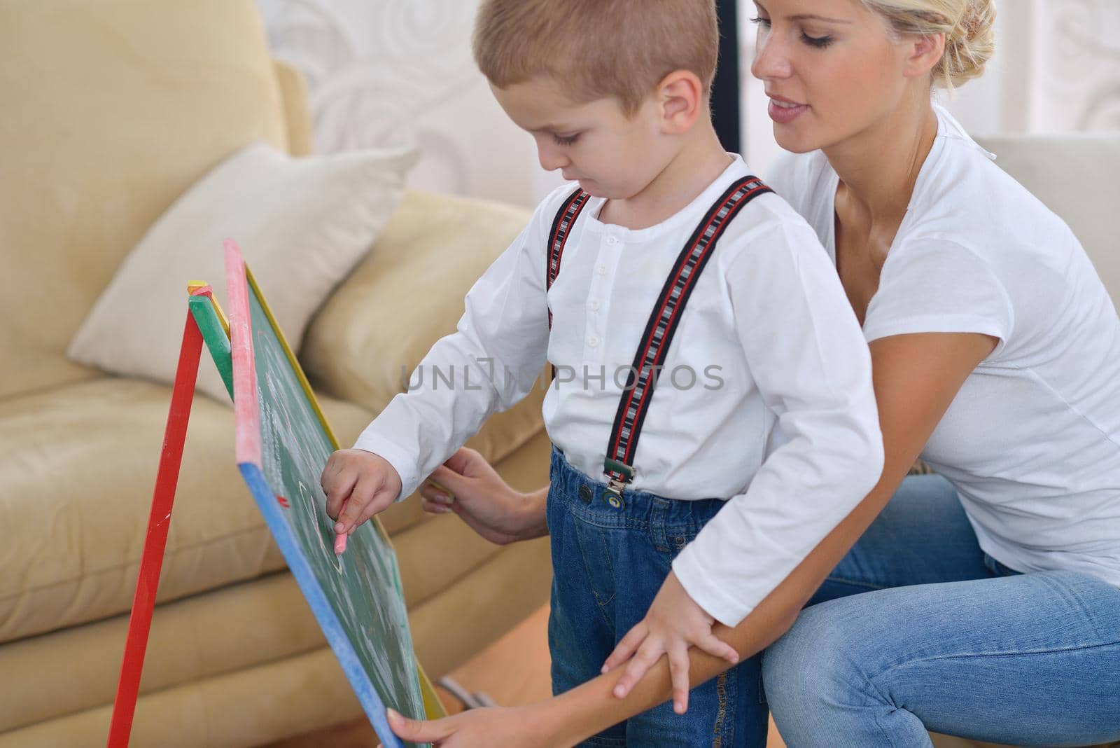 happy young family teach leassons and prepare their son for school while draw on board at home