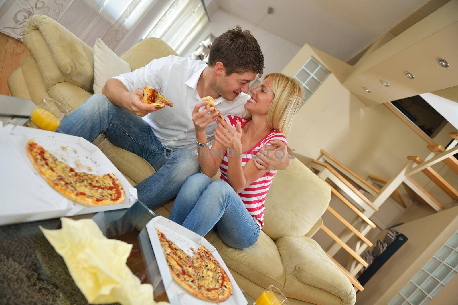 happy young couple eat fresh pizza at home relaxing and watch tv