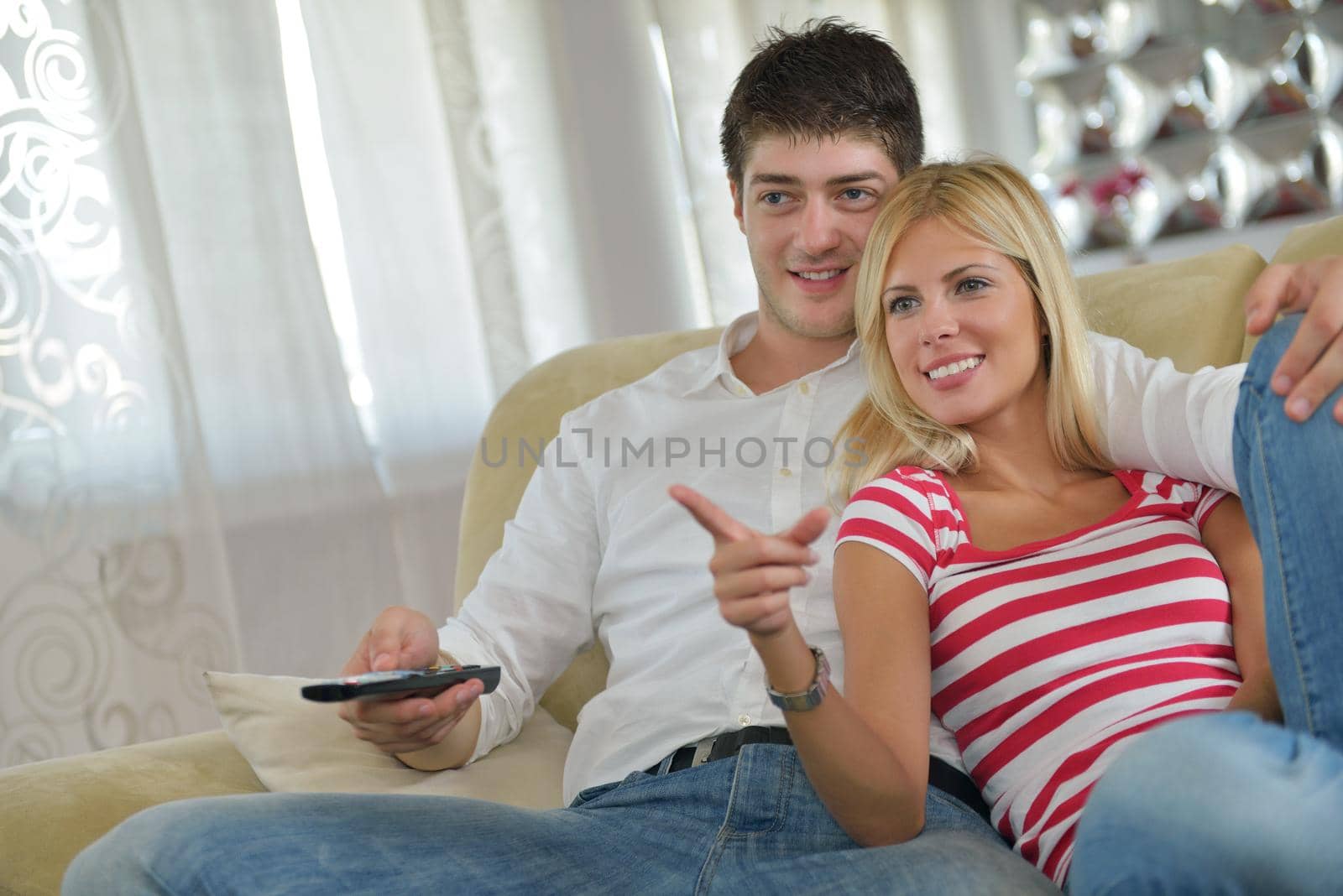 Relaxed young  couple watching tv at home in bright living room