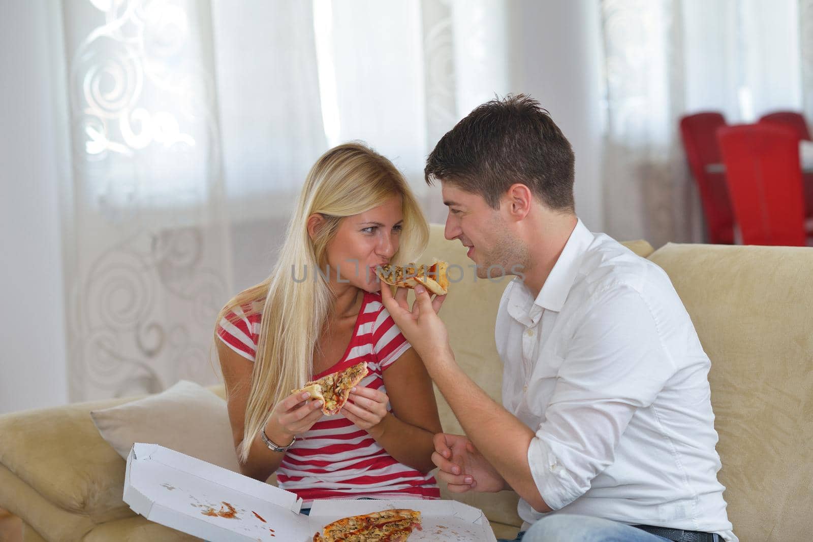 happy young couple eat fresh pizza at home relaxing and watch tv