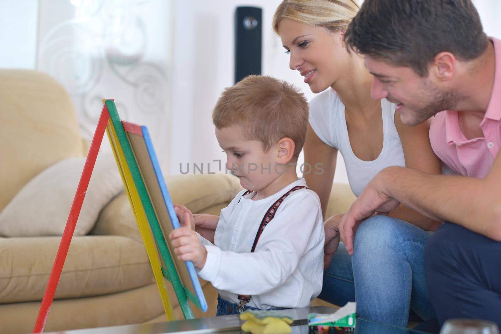 happy young family teach leassons and prepare their son for school while draw on board at home