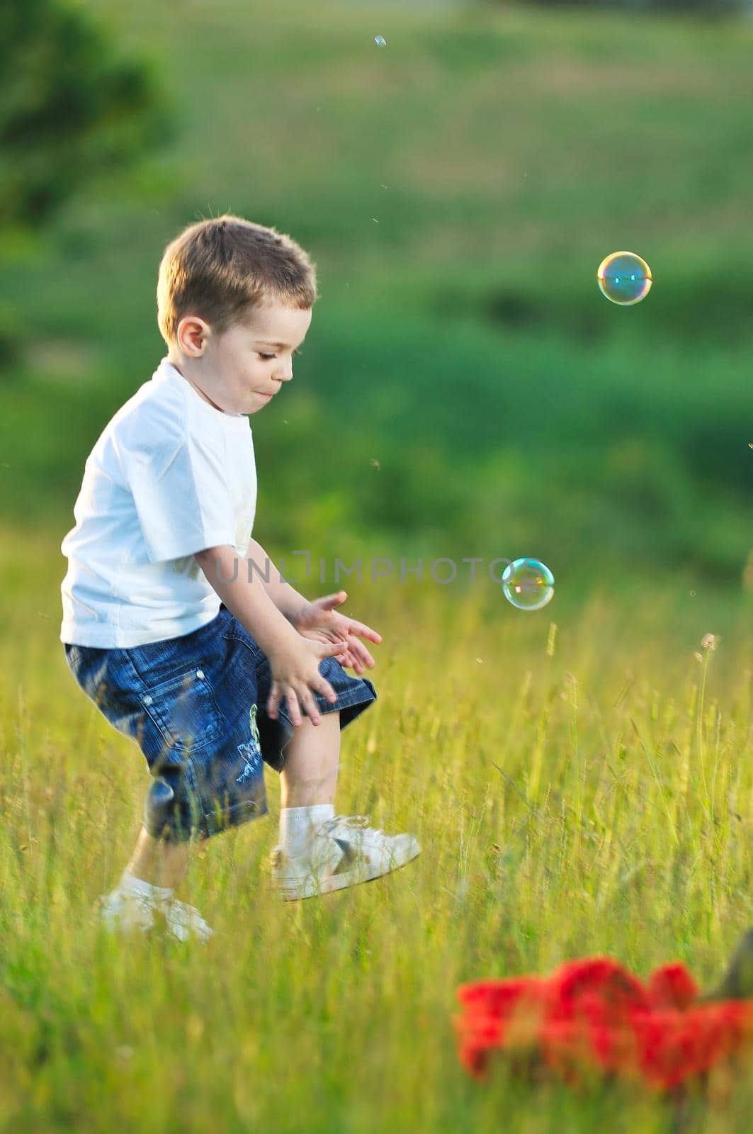 happy young beautiful child have fun on eadow with soap bubbles toy