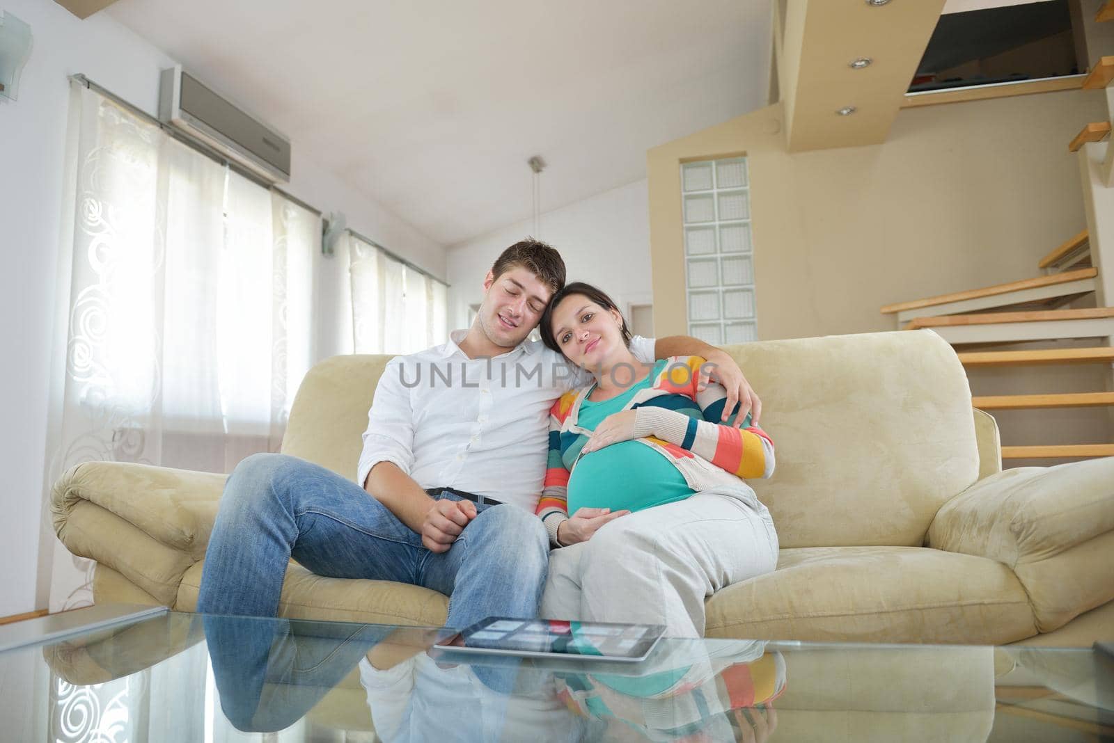 pregnant woman with her husband have fun relax and using tablet comture at modern home