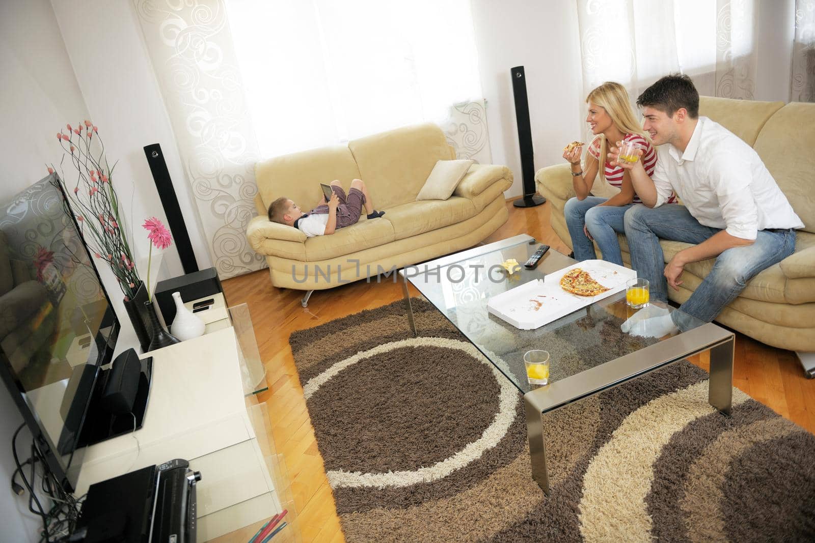 happy young couple eat fresh pizza at home relaxing and watch tv