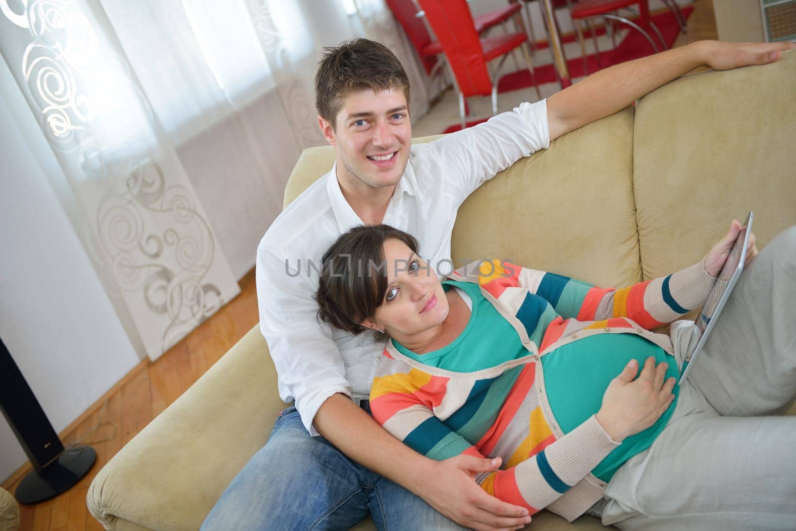pregnant couple at home using tablet computer by dotshock