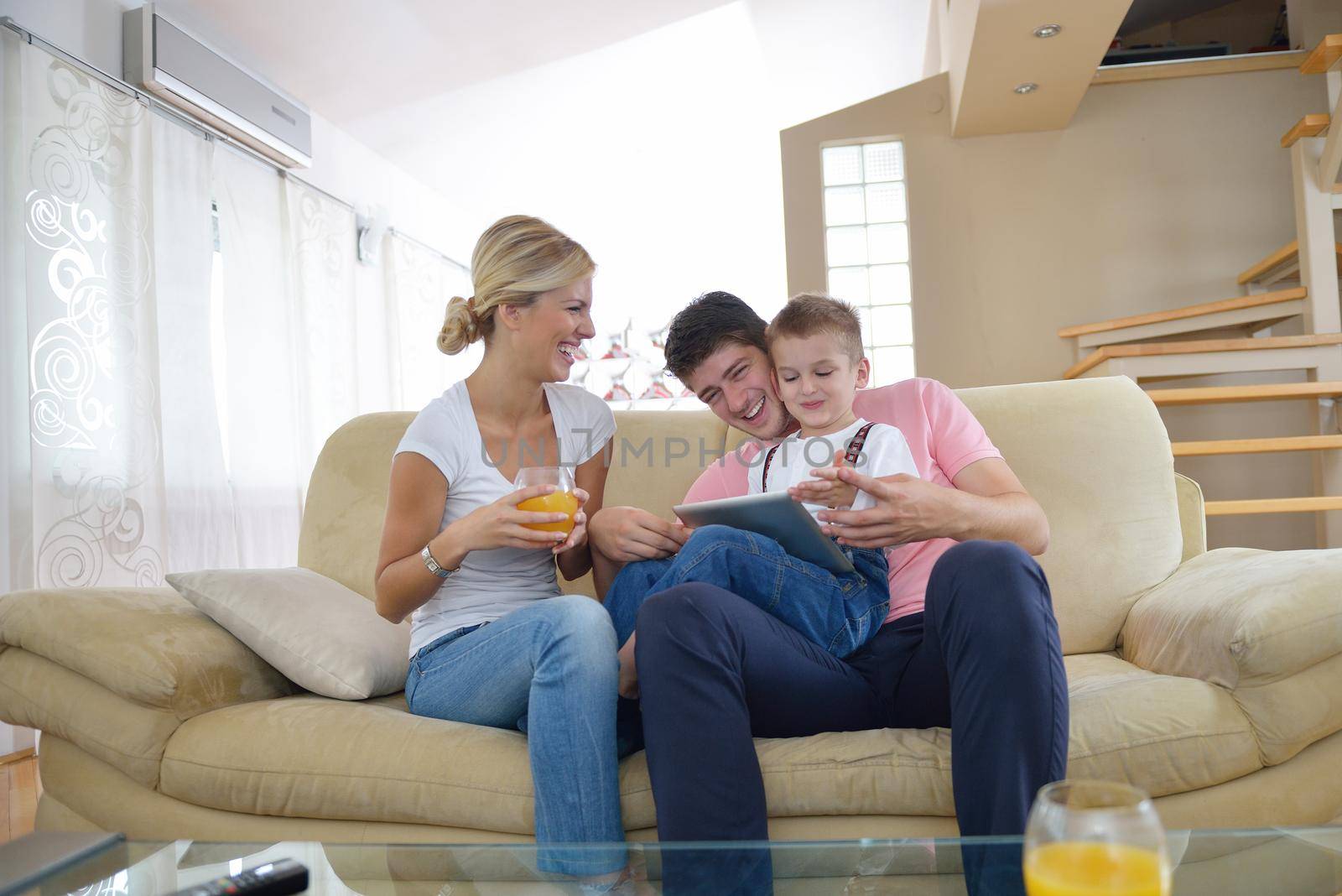 happy young family using tablet computer at modern  home for playing games and education