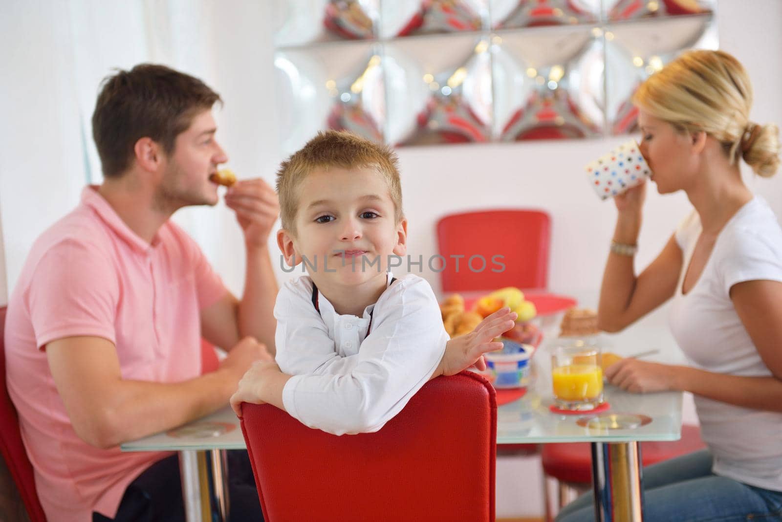 happy young family have healthy breakfast at kitchen with red details on bright morning light