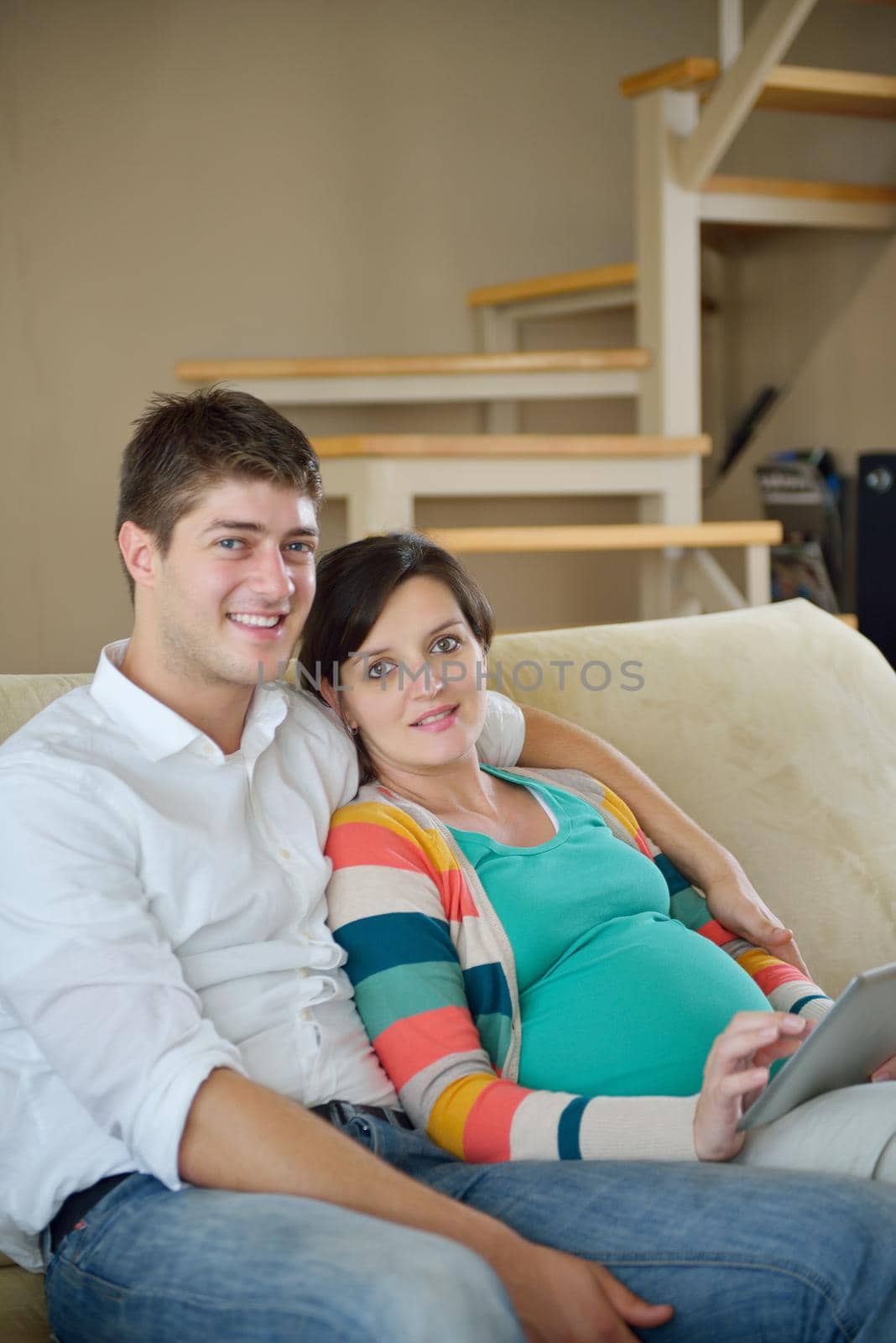 pregnant couple at home using tablet computer by dotshock