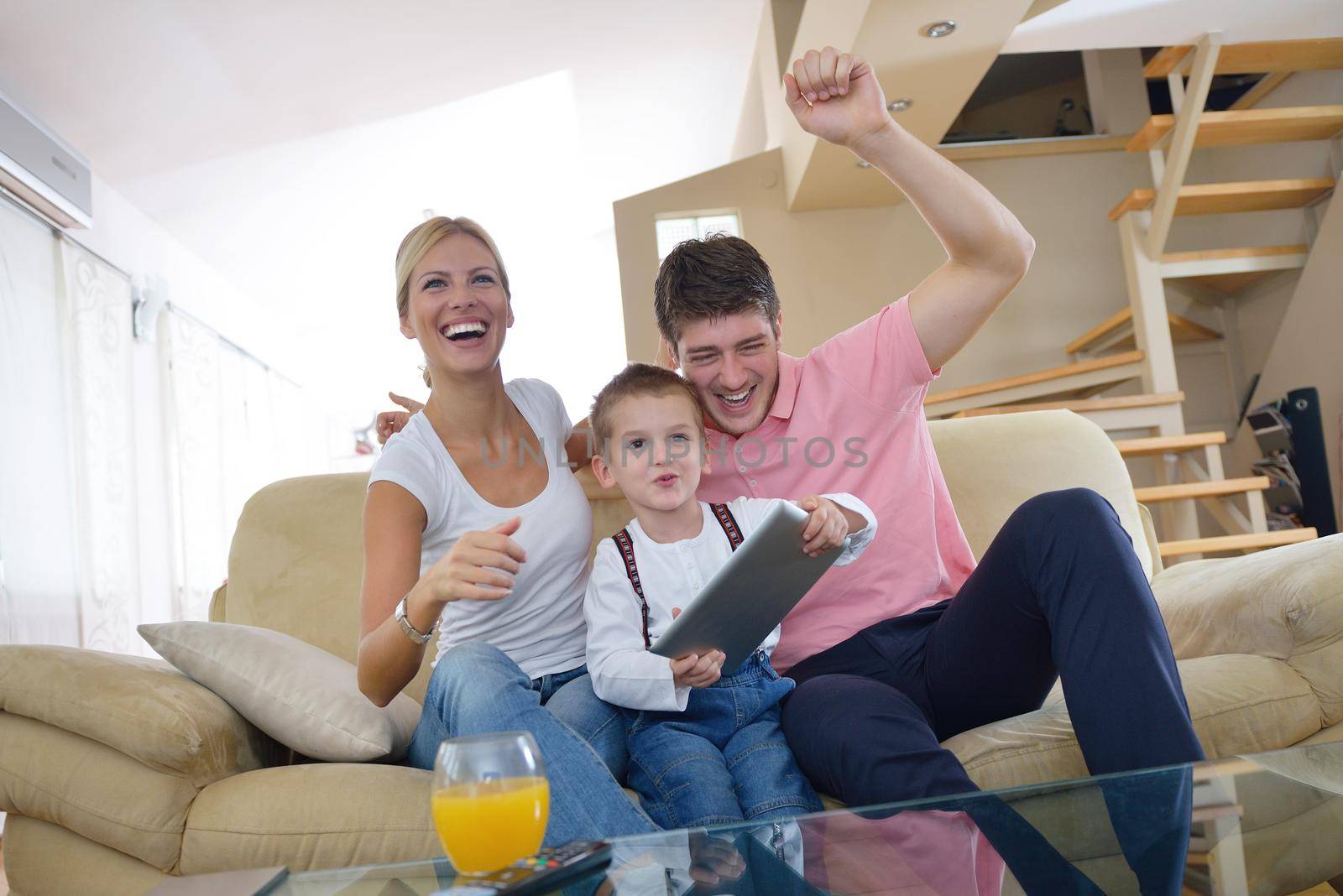 happy young family using tablet computer at modern  home for playing games and education
